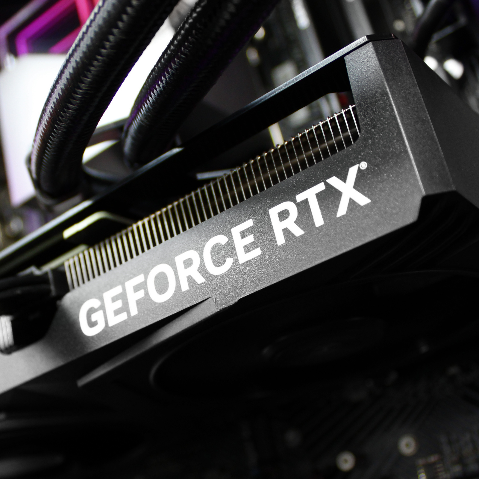 Primer plano de una tarjeta gráfica GeForce RTX negra dentro de un ordenador con componentes visibles.