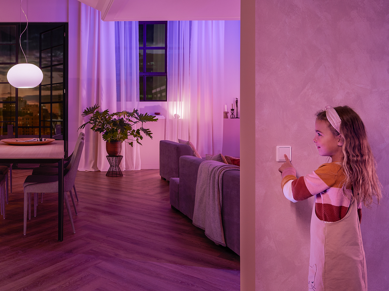 Een meisje schakelt een lichtschakelaar in een kamer in die is verlicht met roze en paars licht.