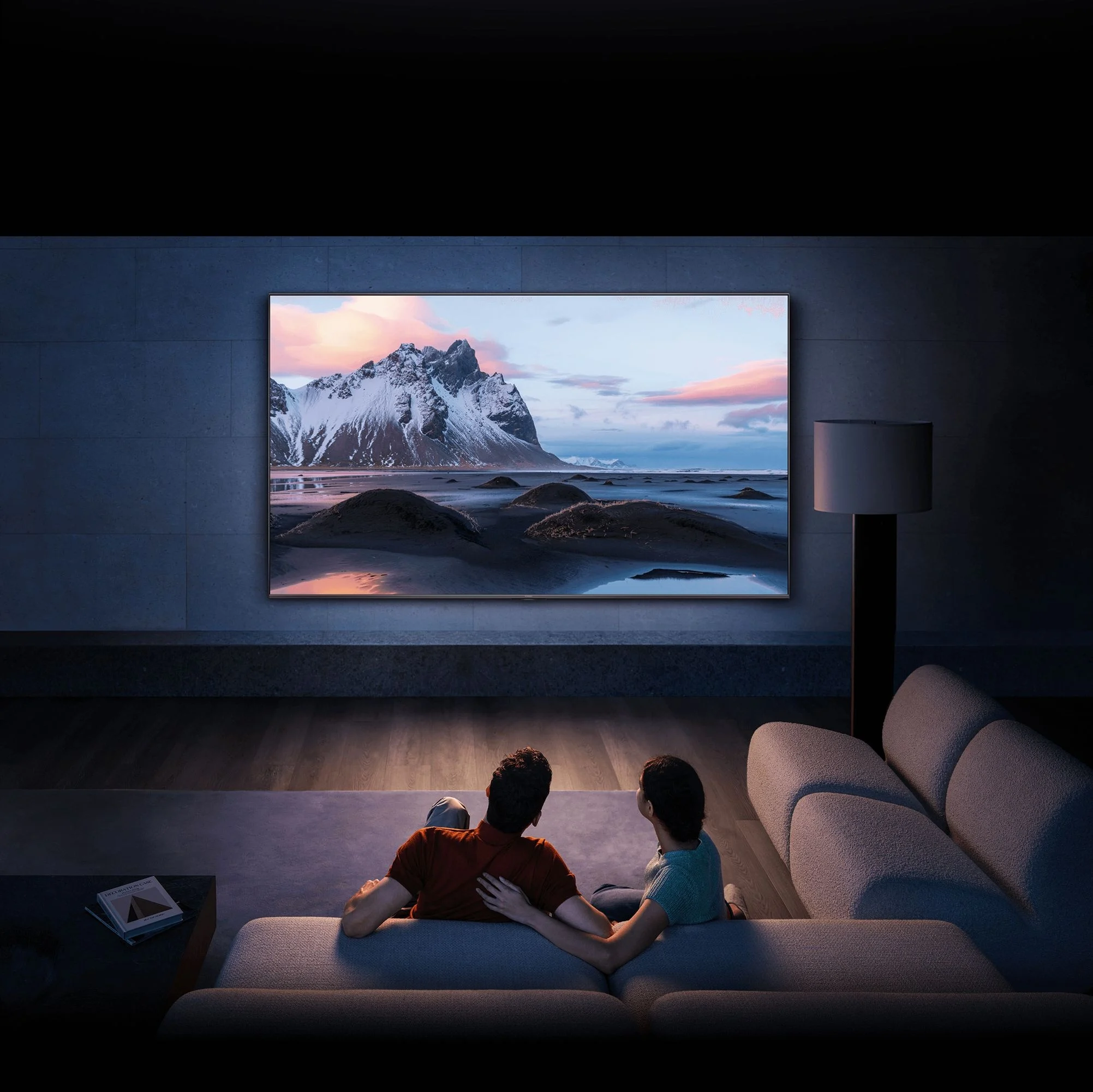 Dwie osoby na kanapie oglądają telewizor z górami.