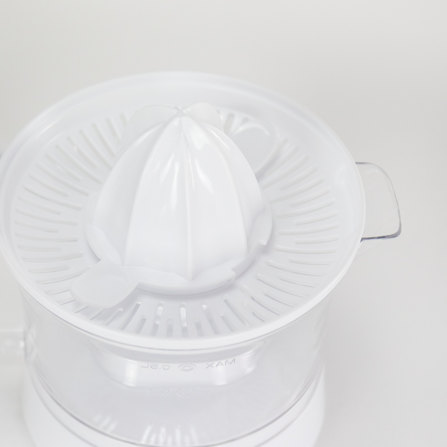 Exprimidor de cítricos blanco, vista superior, con un reamer y colador blancos.