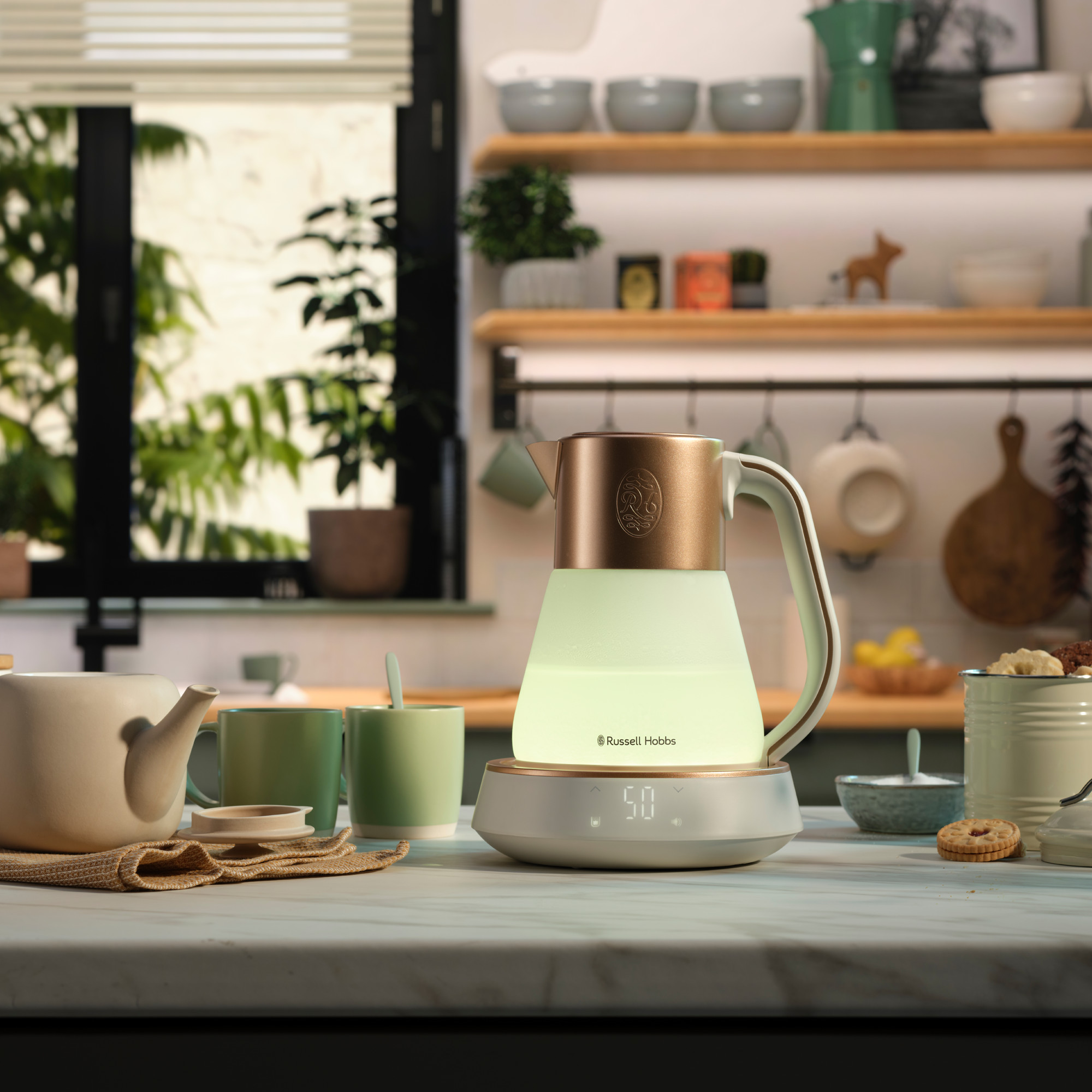 Bollitore elettrico su una superficie bianca. Testo: Russell Hobbs. Il bollitore è vicino a tazze e biscotti.
