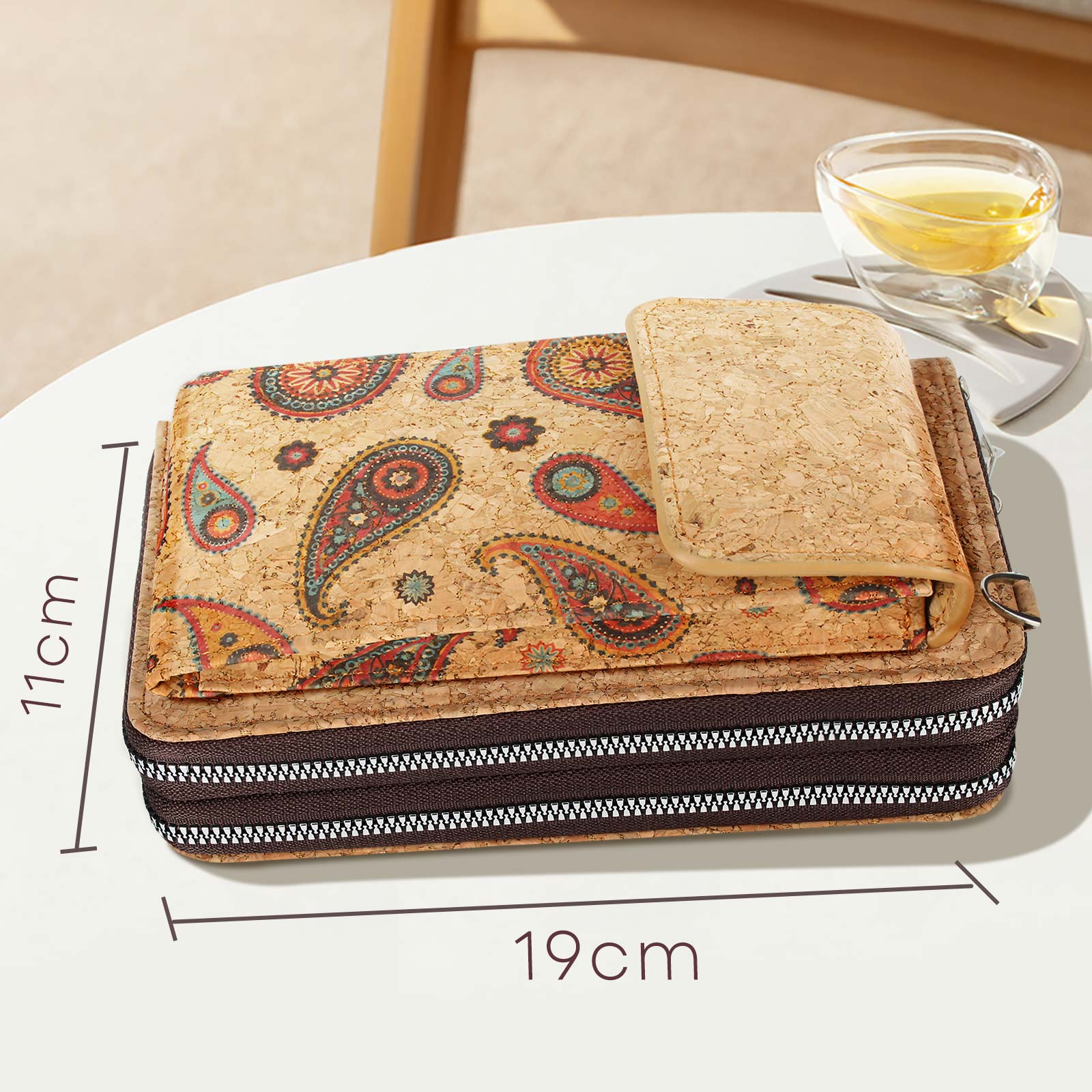 Kork-Geldbörse mit Paisley-Muster auf einem weißen Tisch. Neben einem Glas Tee.