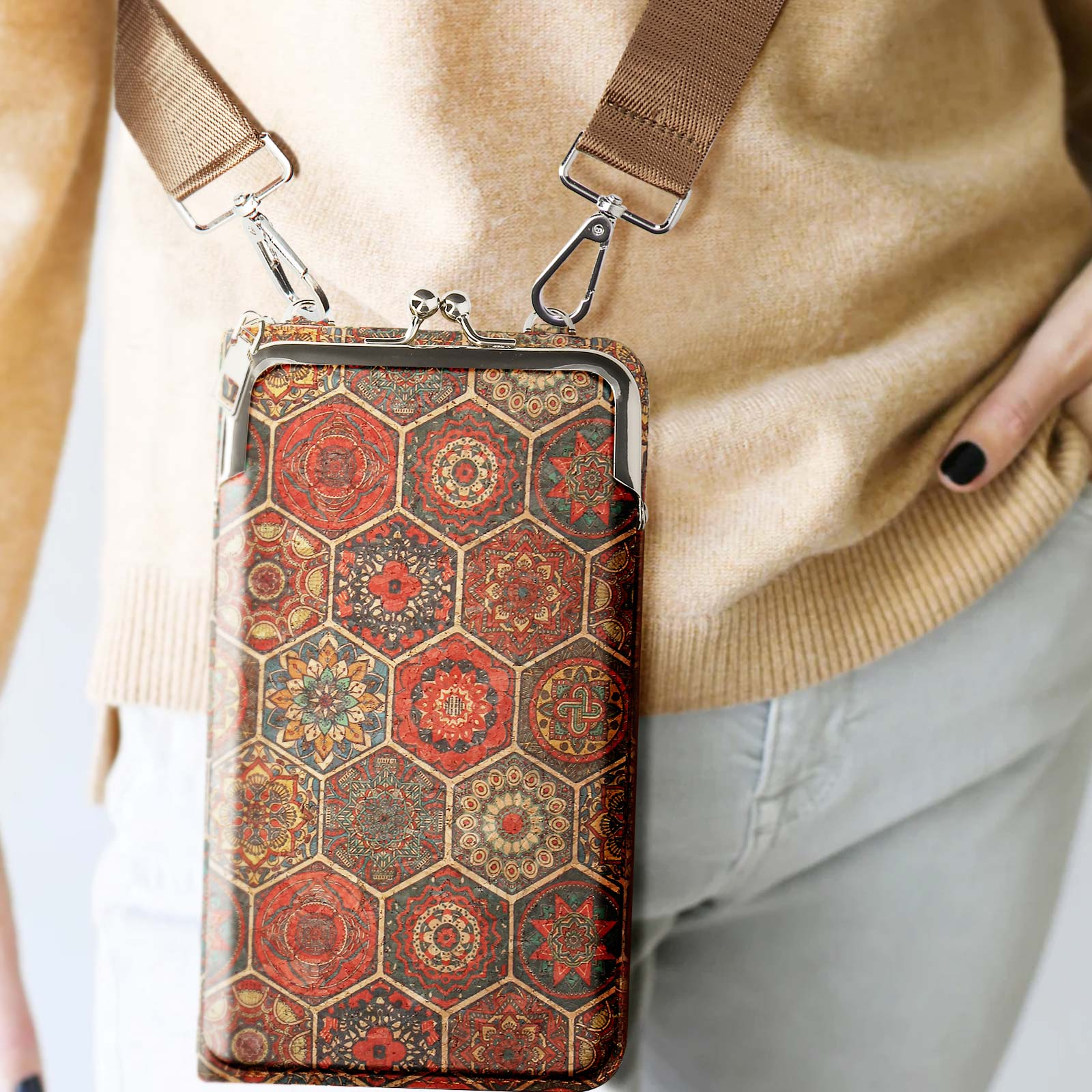 Eine gemusterte Telefontasche mit Riemen. Von einer Person getragen. Der Hintergrund ist neutral.