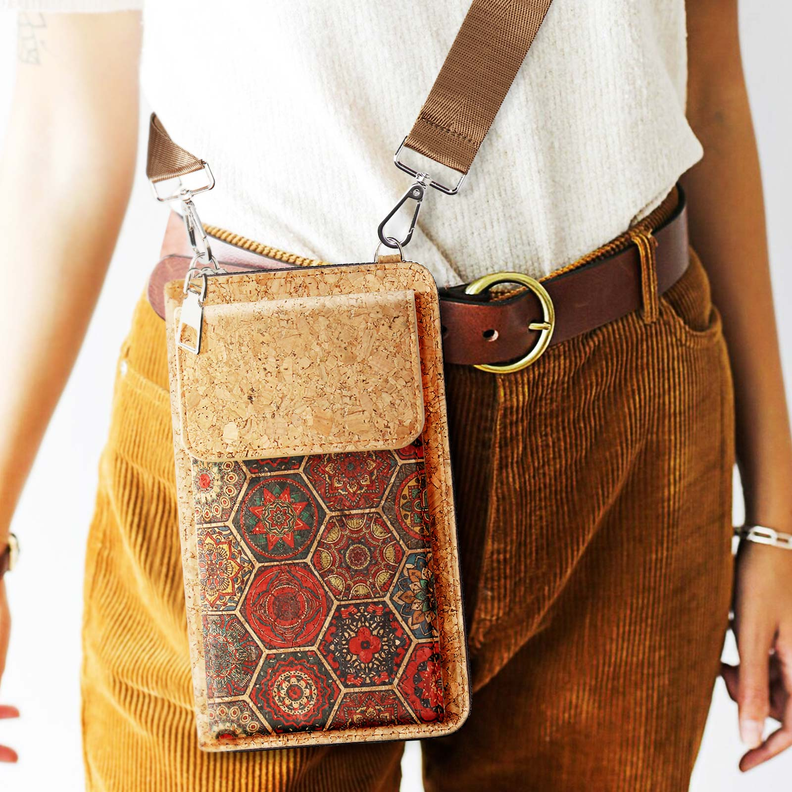 Person trägt eine Kork-Handytasche über Cordhosen und einem Gürtel. Die Tasche hat ein Blumendesign.