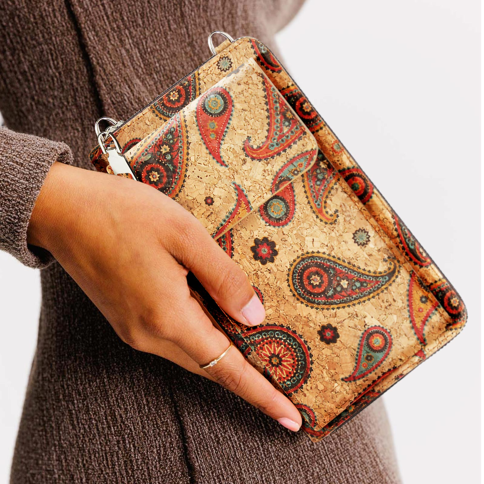 Hand hält eine Korkbrieftasche mit Paisley-Muster, eine kleinere Brieftasche davor.