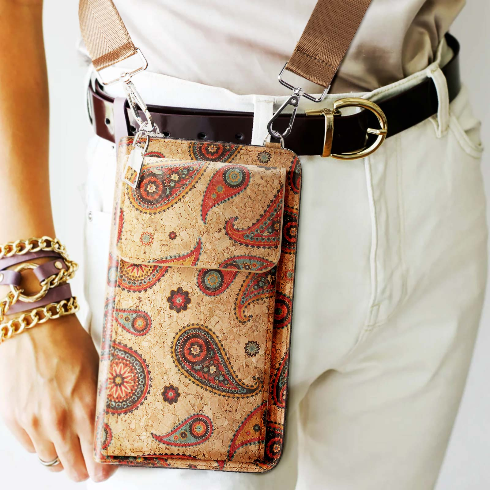 Eine Person, die eine Handytasche mit dekorativem Muster trägt, die Tasche hängt an einem Riemen.