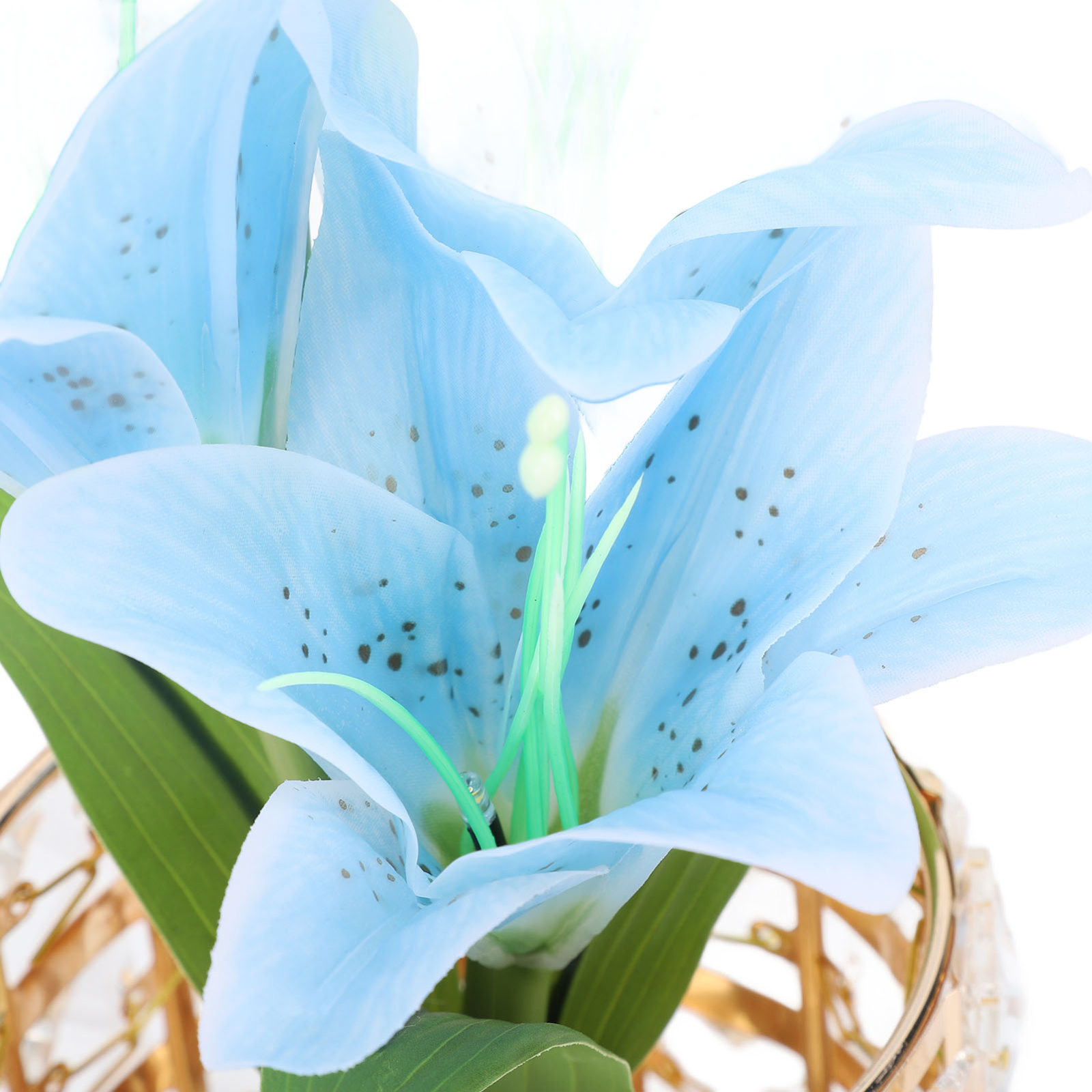 Nahaufnahme von hellblauen künstlichen Lilien in einer goldfarbenen dekorativen Vase.