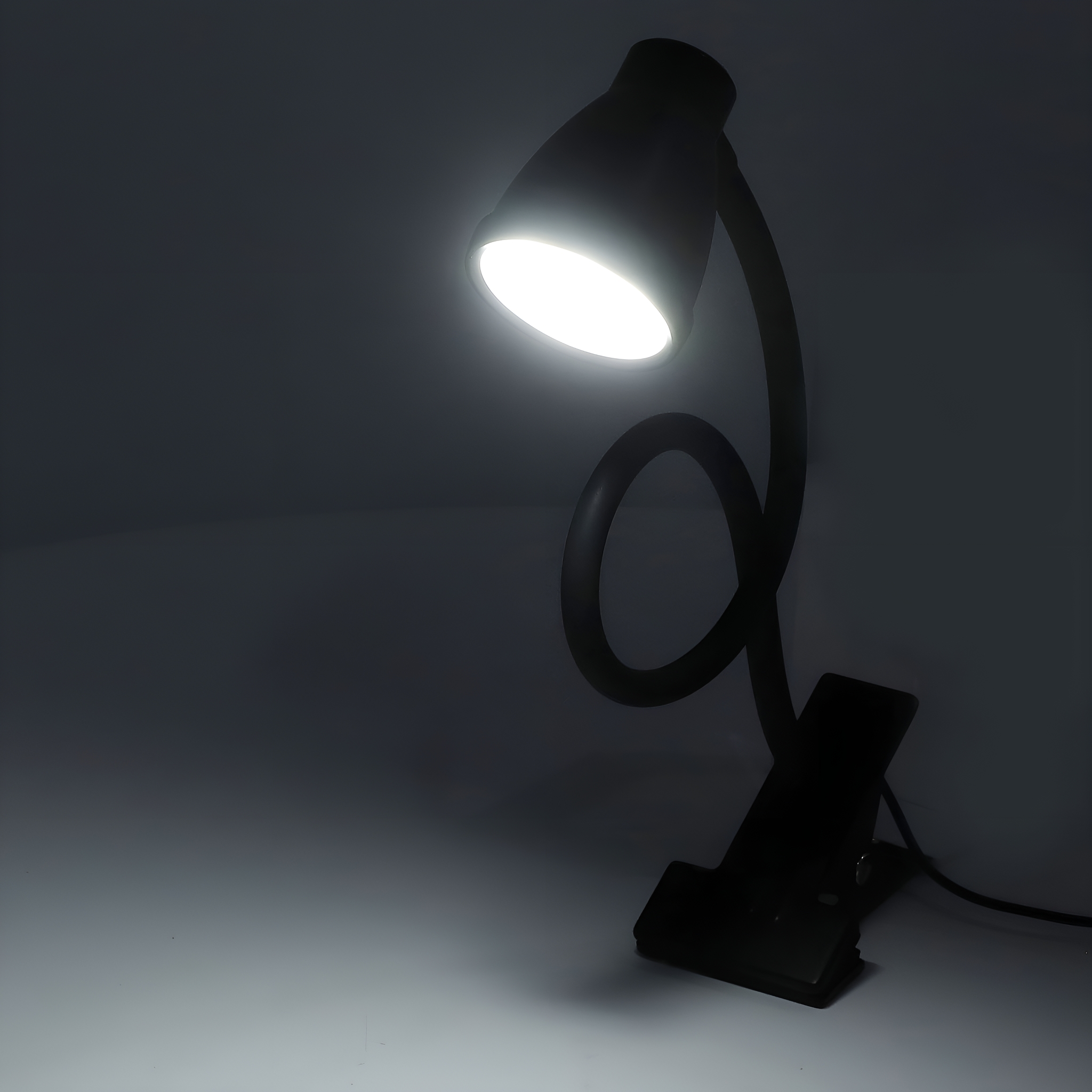 Schwarze Schreibtischlampe mit hellem Licht, schwarzer Hintergrund.