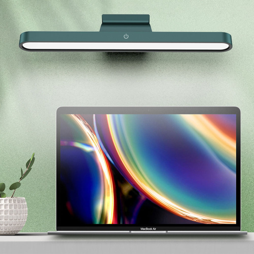 Ein Laptop auf einem Tisch mit einer Lampe darüber. Die Lampe und der Laptop sind im Fokus.