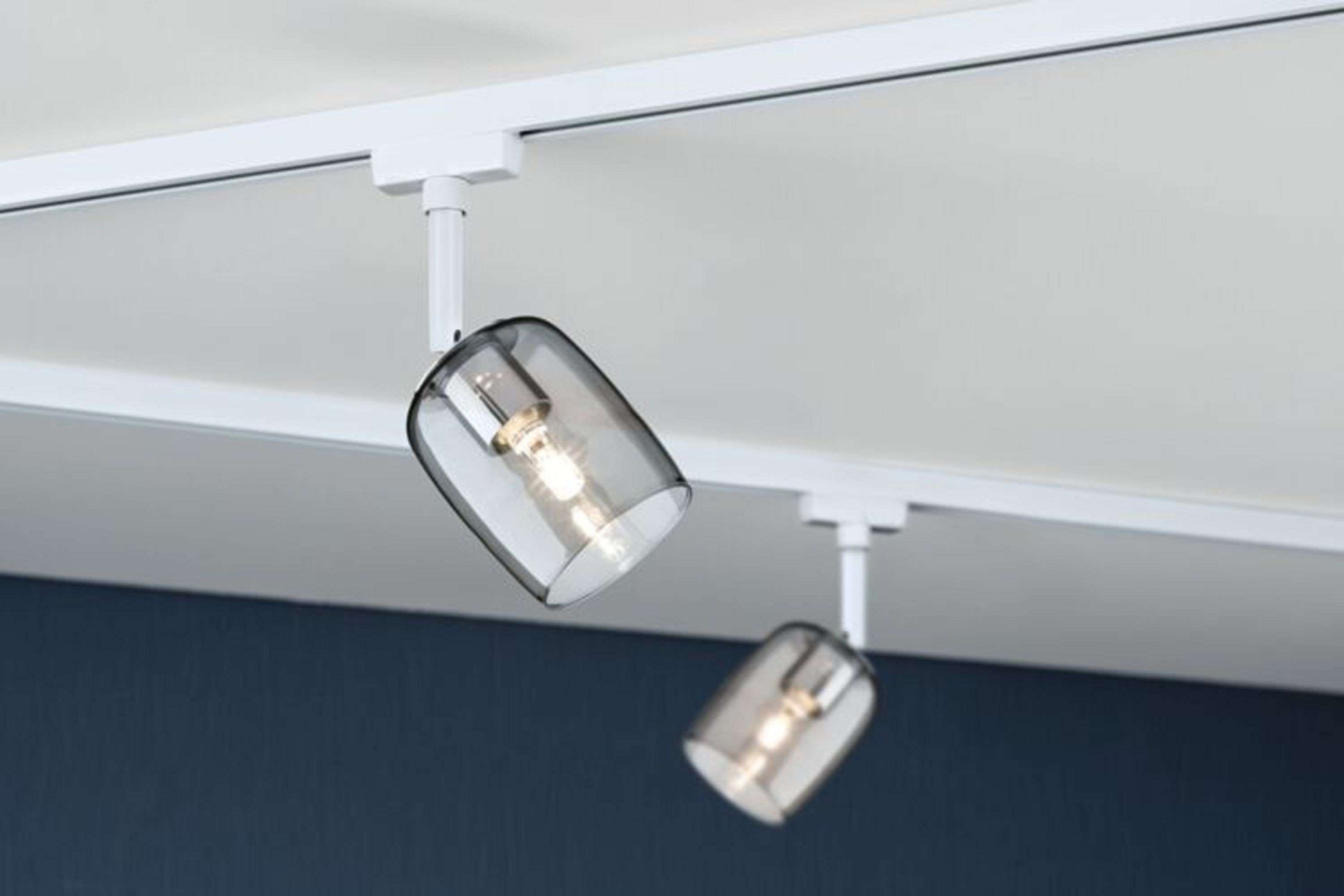 Zwei Pendelleuchten mit rauchfarbenen Glasschirmen hängen an einer weißen Deckenschiene.