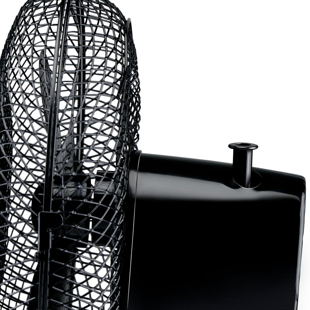Ventilateur noir avec un couvercle en treillis métallique. Base et corps noirs, fond blanc. Gros plan.