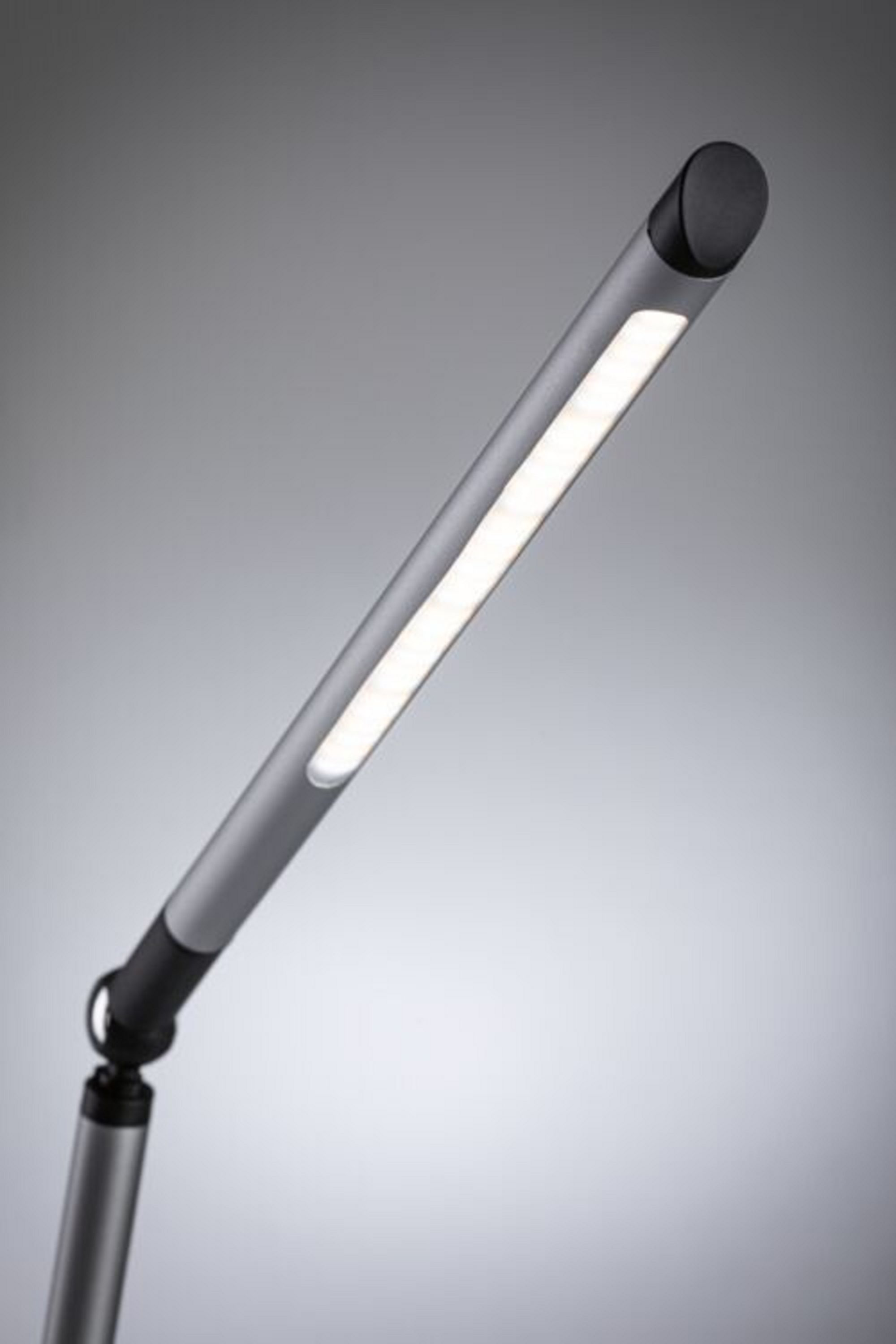 Una lampada da scrivania argentata con una lunga barra luminosa angolata e una base nera. Su sfondo grigio.
