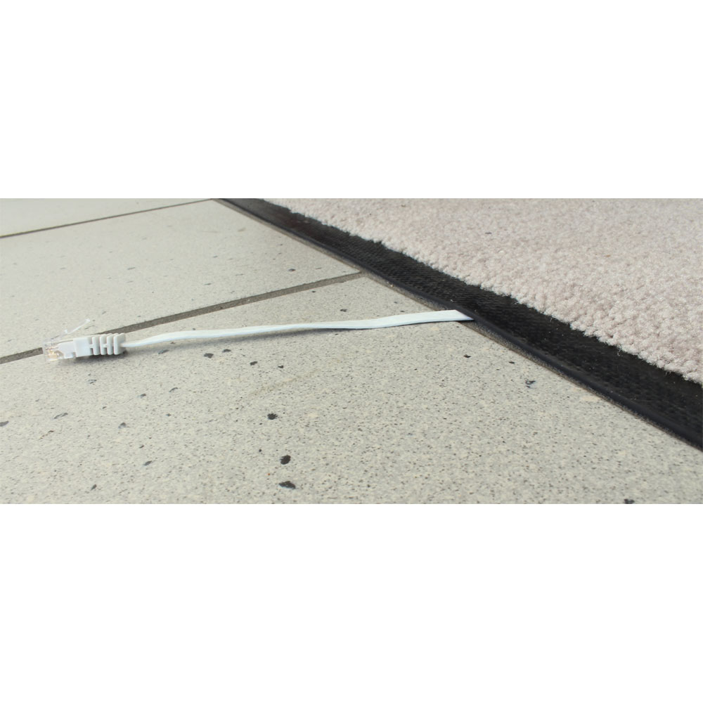 Un câble Ethernet blanc sortant d'une dalle, à côté d'un tapis.