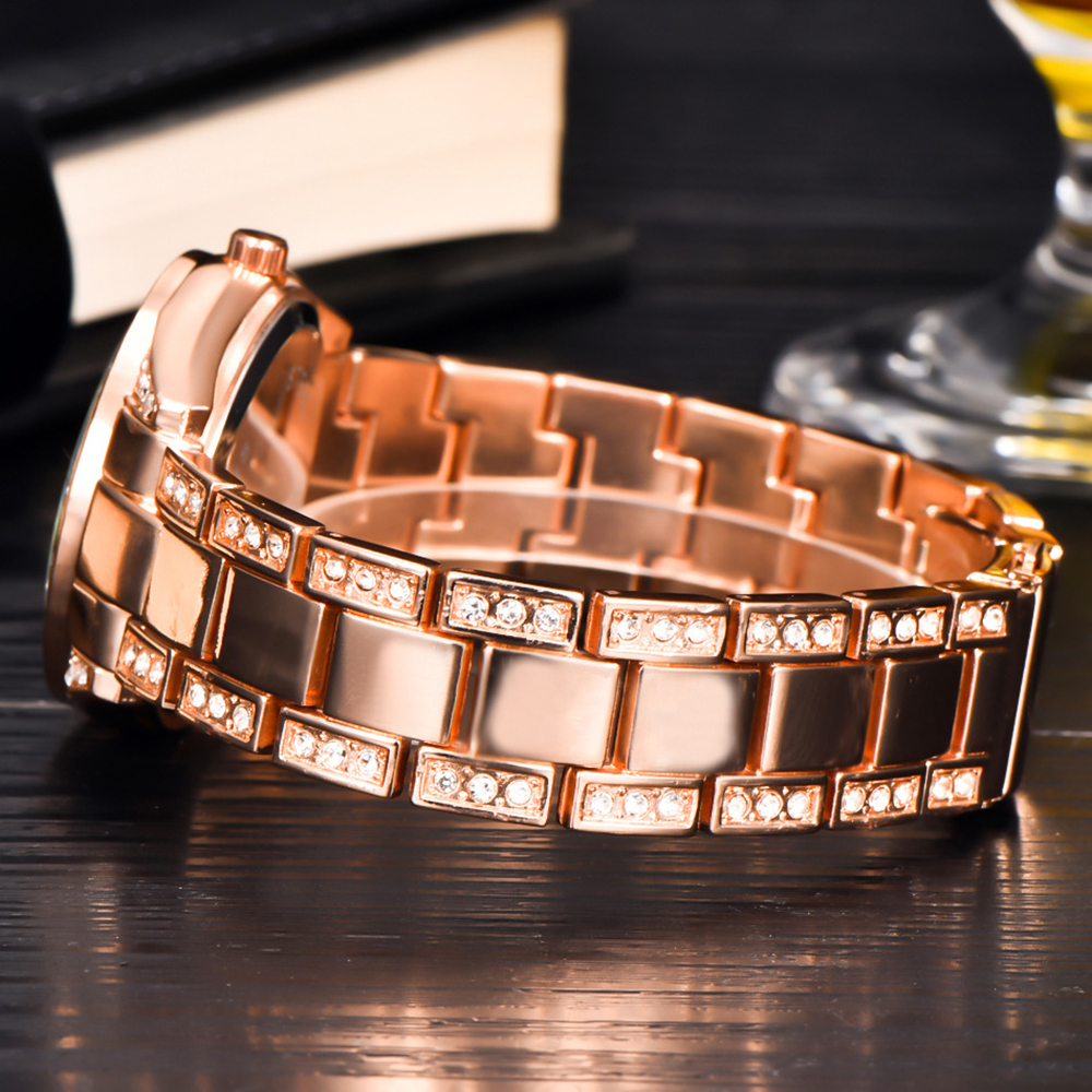 Roségoldene Uhr mit diamantbesetztem Band, auf dunkler Holzoberfläche, Nahaufnahme.