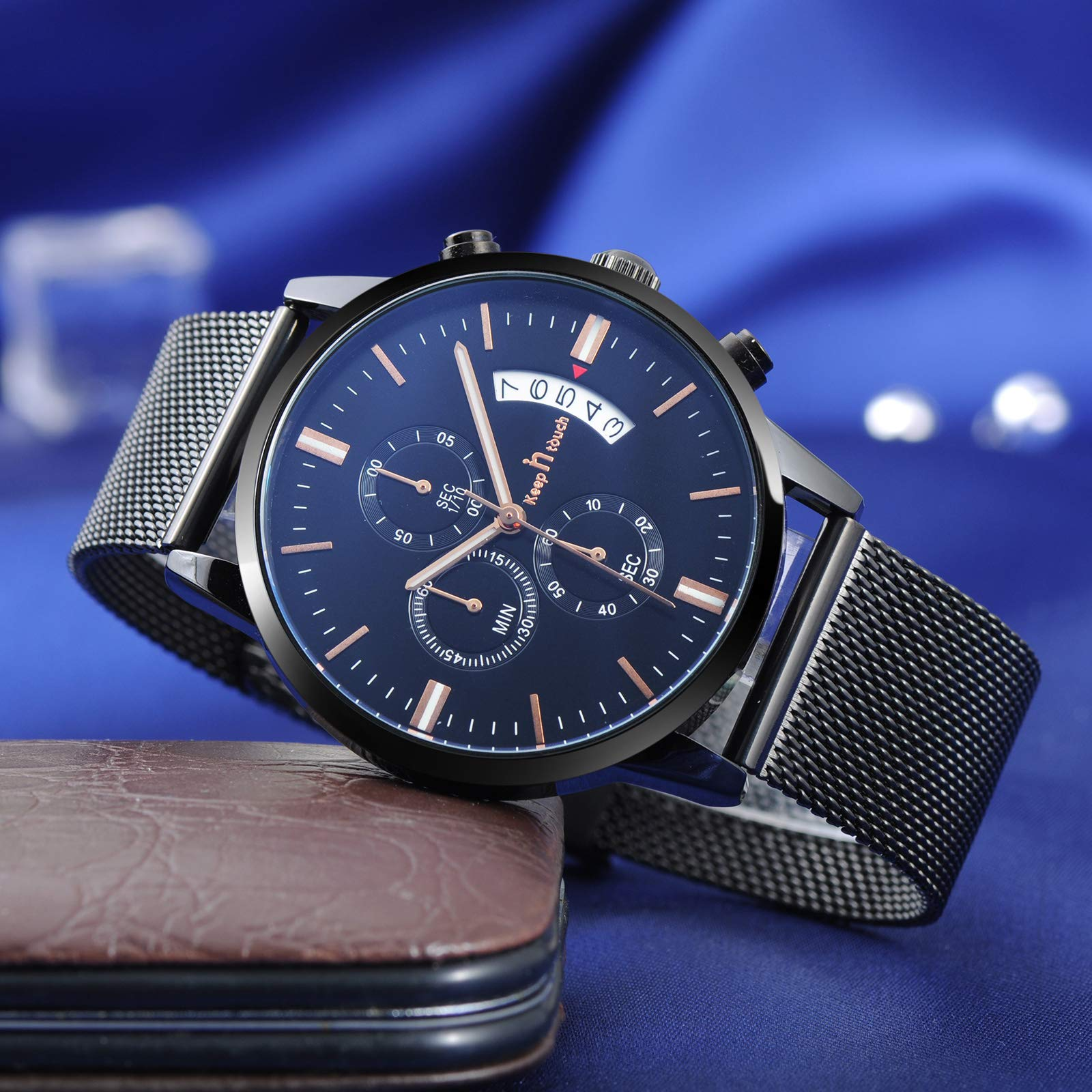 Eine schwarze Uhr mit dunkelblauem Zifferblatt und silbernem Armband, auf brauner Oberfläche.
