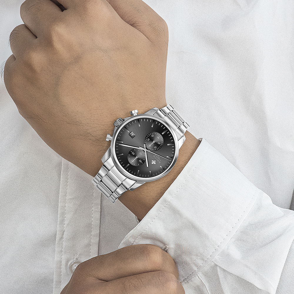 Ein Mann trägt eine silberne Uhr mit dunklem Zifferblatt.
