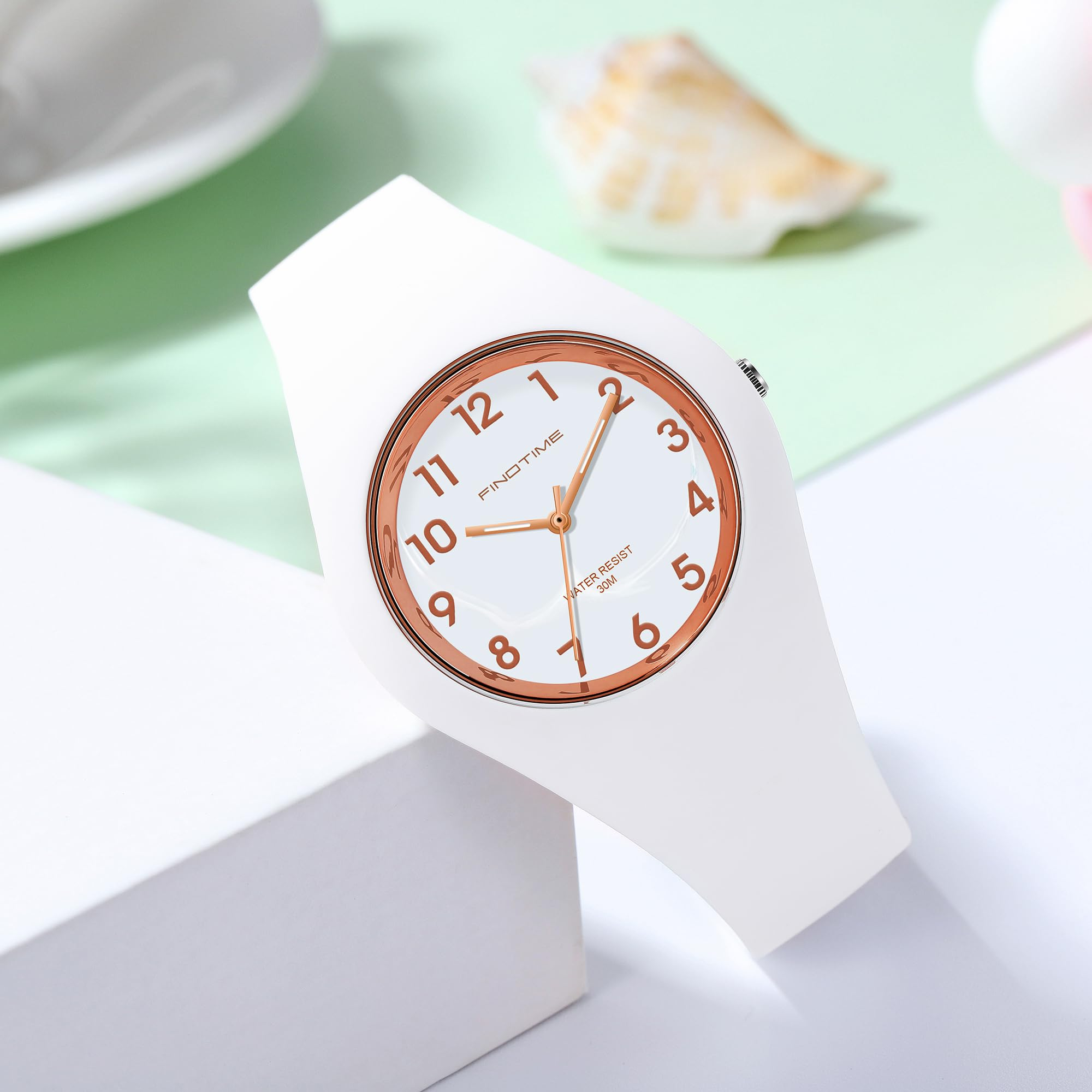 Eine weiße Uhr mit weißem Armband und roségoldfarbenem Zifferblatt.