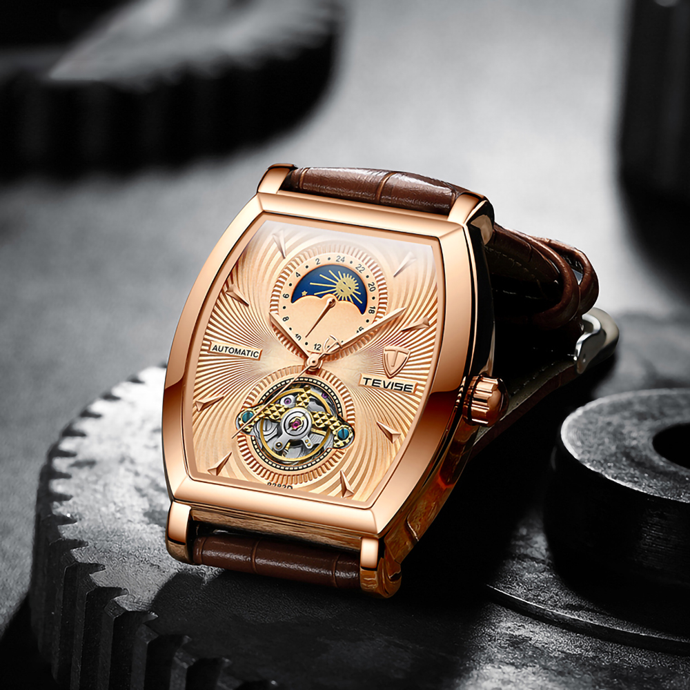 Goldene Uhr mit braunem Lederarmband. Sie befindet sich auf einem strukturierten, metallischen Hintergrund, Nahaufnahme.