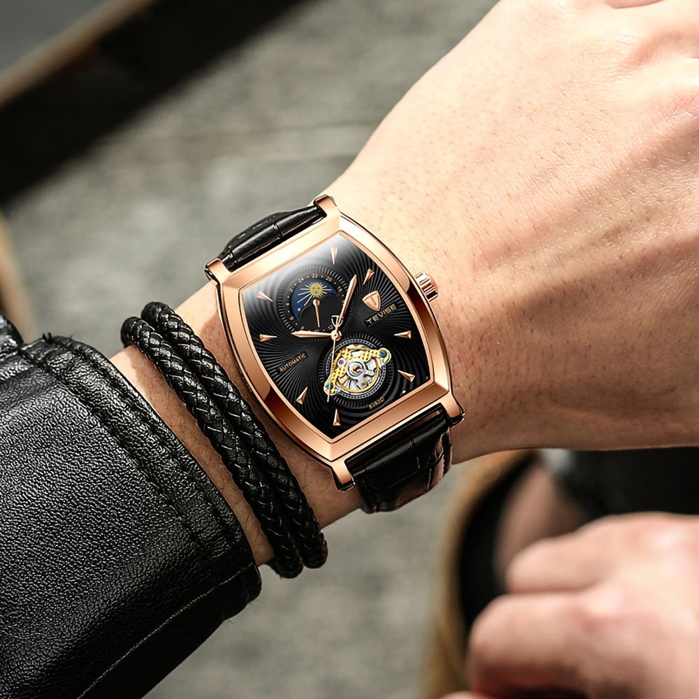 Das Handgelenk eines Mannes mit einer goldenen Uhr und einem Lederarmband. Schwarze Lederjacke.