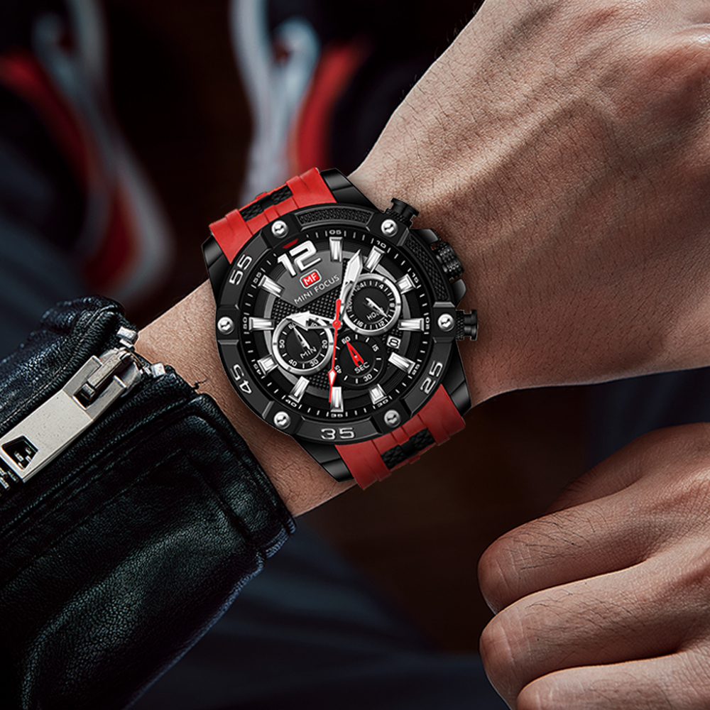 Das Handgelenk eines Mannes mit einer schwarz-roten Uhr. Die Uhr hat ein schwarzes Zifferblatt und ein rotes Armband.