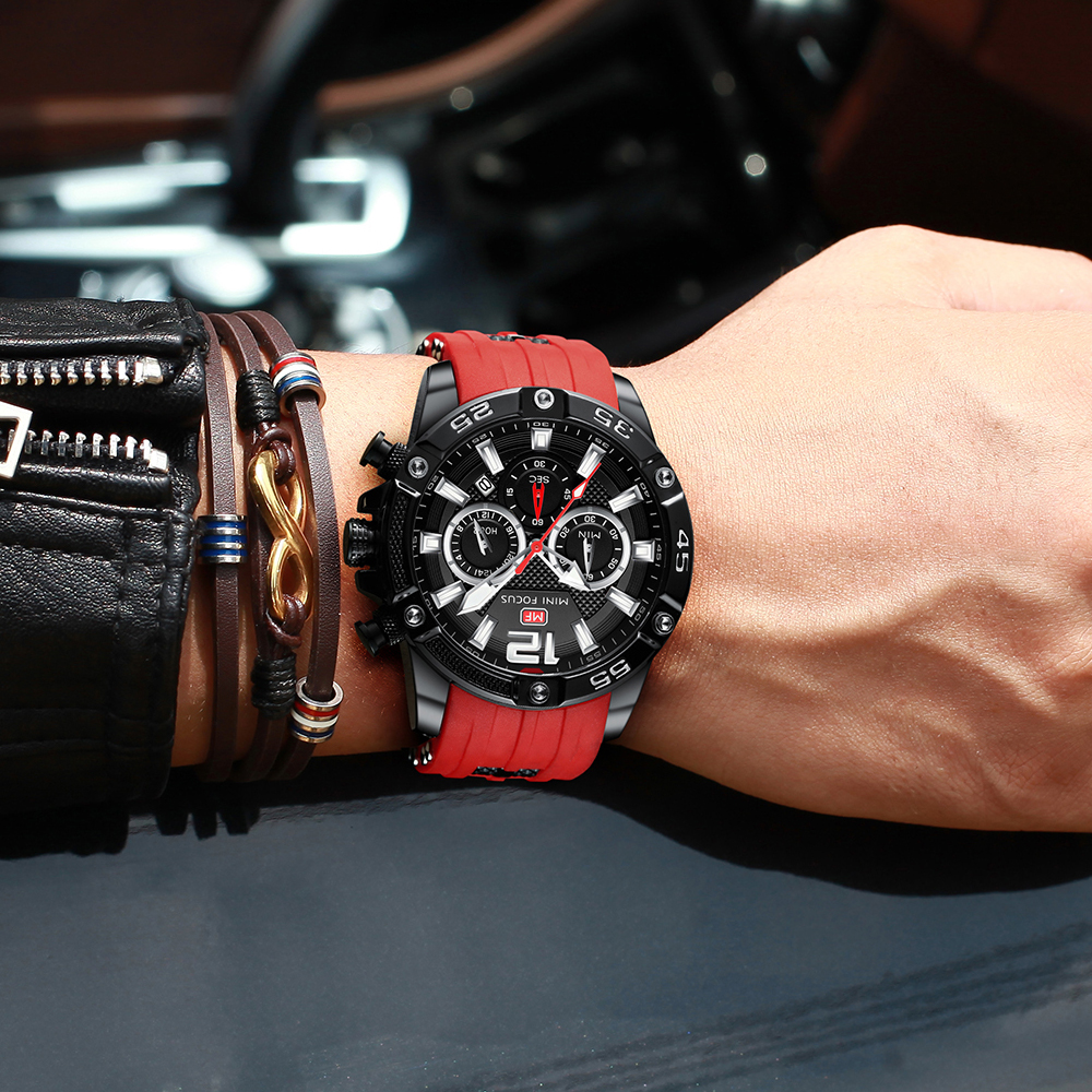 Mann trägt eine schwarze Uhr mit rotem Armband und mehrere Armbänder.