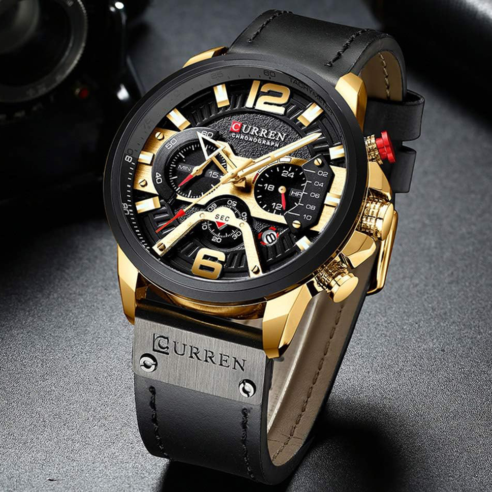 Goldene und schwarze Uhr mit schwarzem Lederarmband. Das Zifferblatt zeigt Zeit und Chronographendetails.