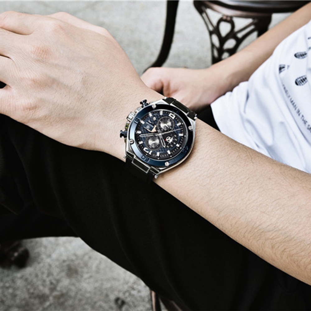 Das Handgelenk einer Person mit einer schwarzen Uhr. Die Uhr hat ein schwarzes Armband und blaue Akzente.
