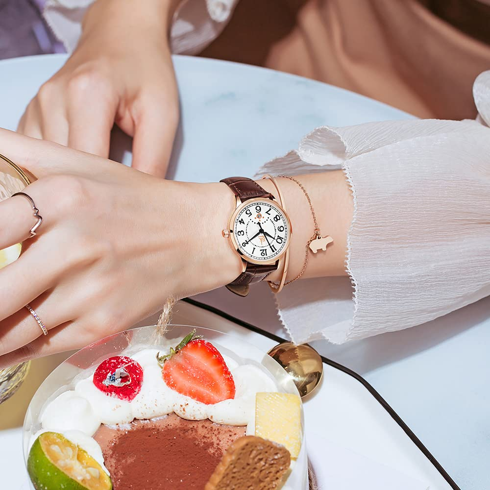 Hand einer Frau mit Uhr und Armband, Kuchen mit Früchten, hellblauer Tisch.