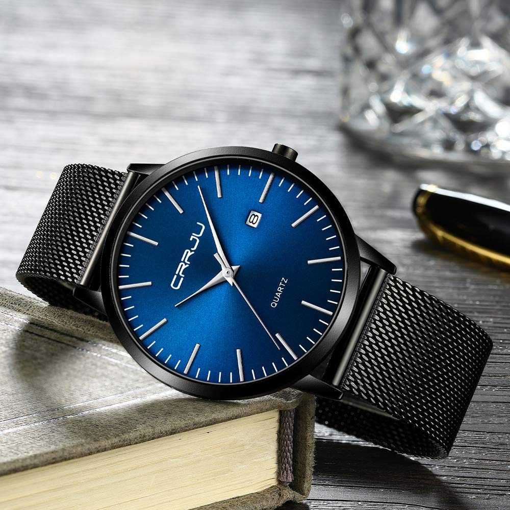 Schwarze Uhr mit blauem Zifferblatt und silbernen Zeigern, auf heller Oberfläche.