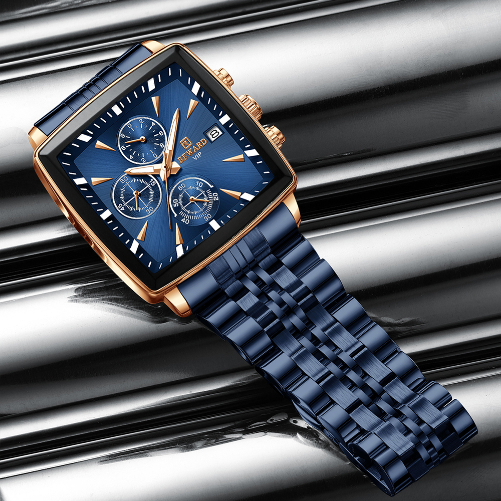 Eine blaue und goldene quadratische Uhr mit blauem Metallarmband auf einer reflektierenden Metalloberfläche.
