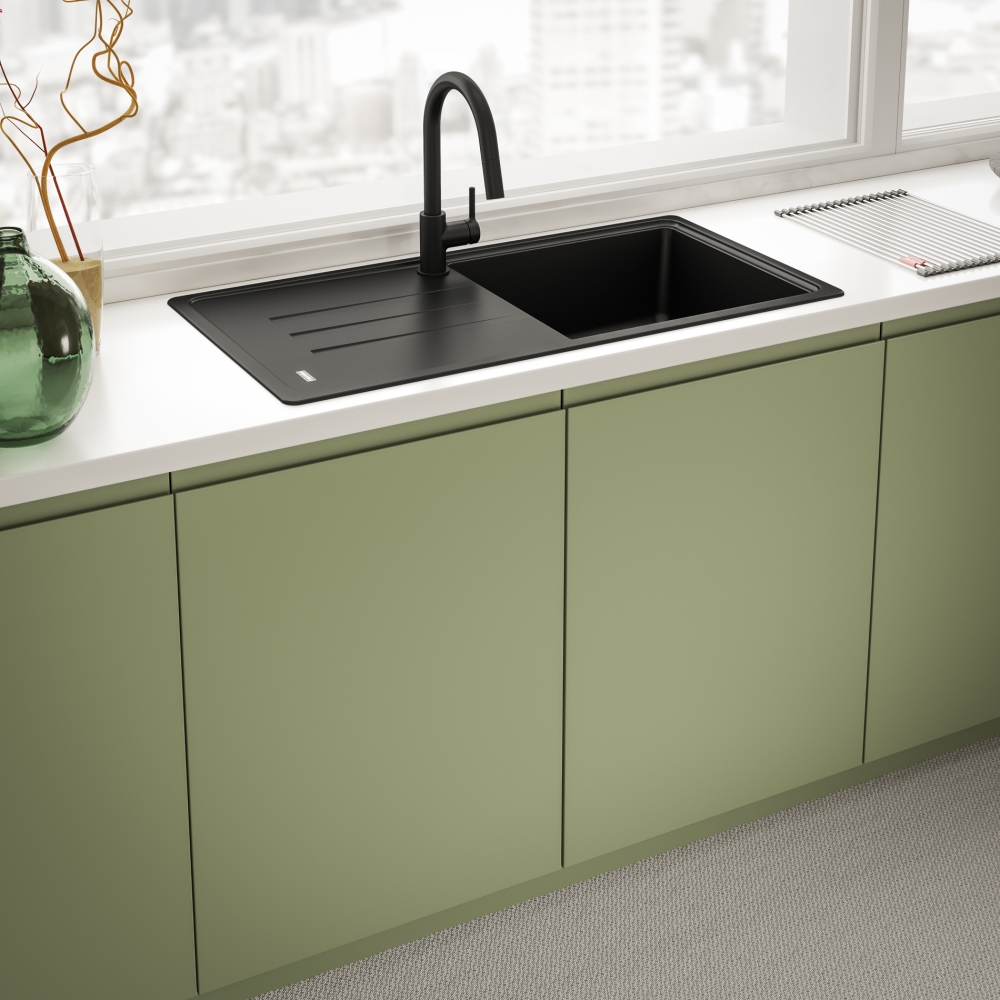 Lavello da cucina nero con rubinetto su piano di lavoro bianco, sotto la luce della finestra.