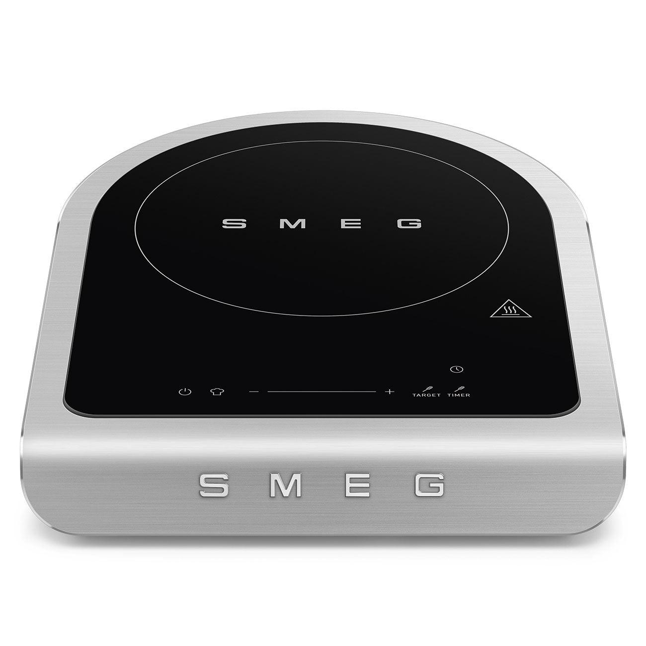 Ein silbernes SMEG-Induktionskochfeld auf weißem Hintergrund. Das Kochfeld hat eine schwarze Kochfläche.