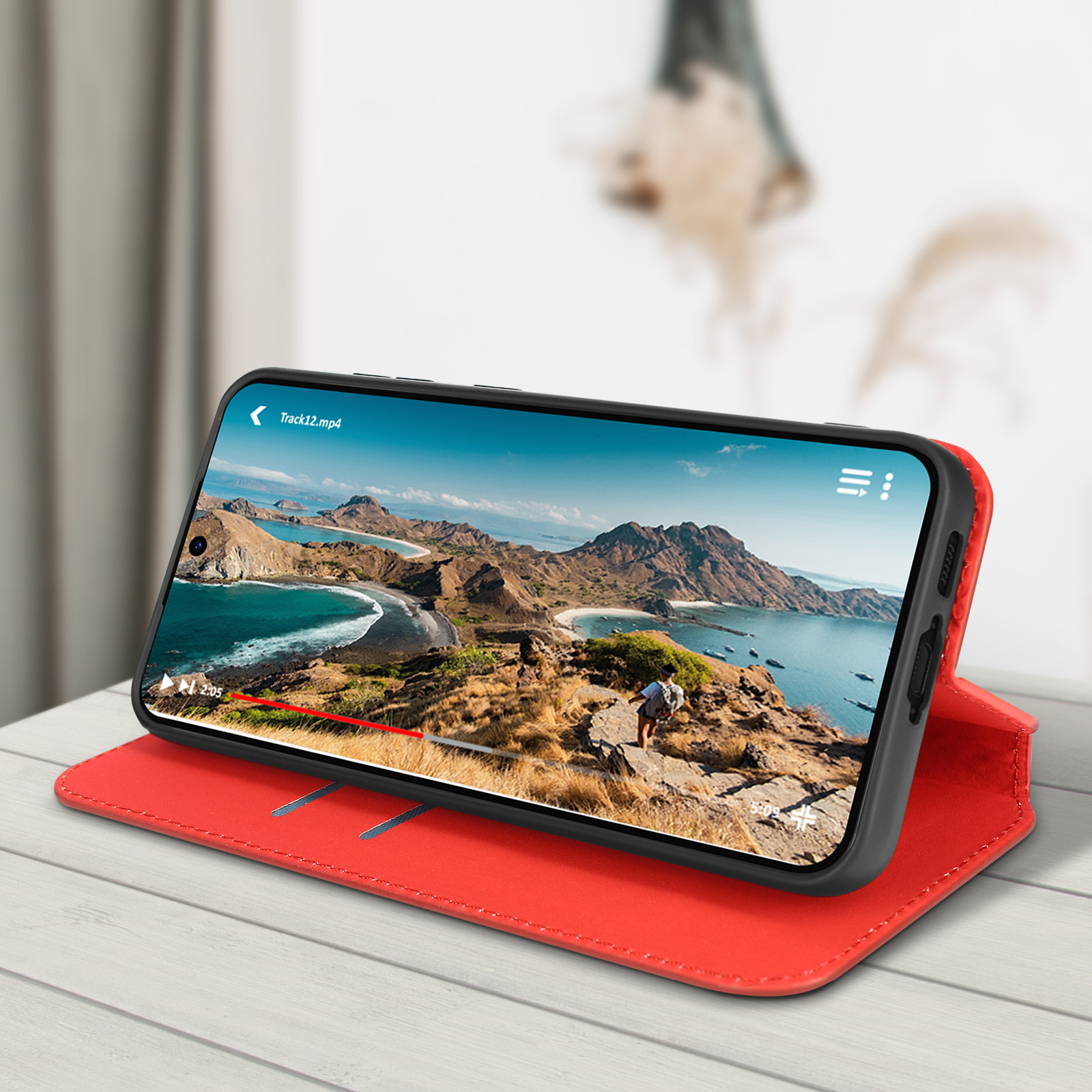 Smartphone in custodia rossa, mostra un video, con sfondo panoramico.