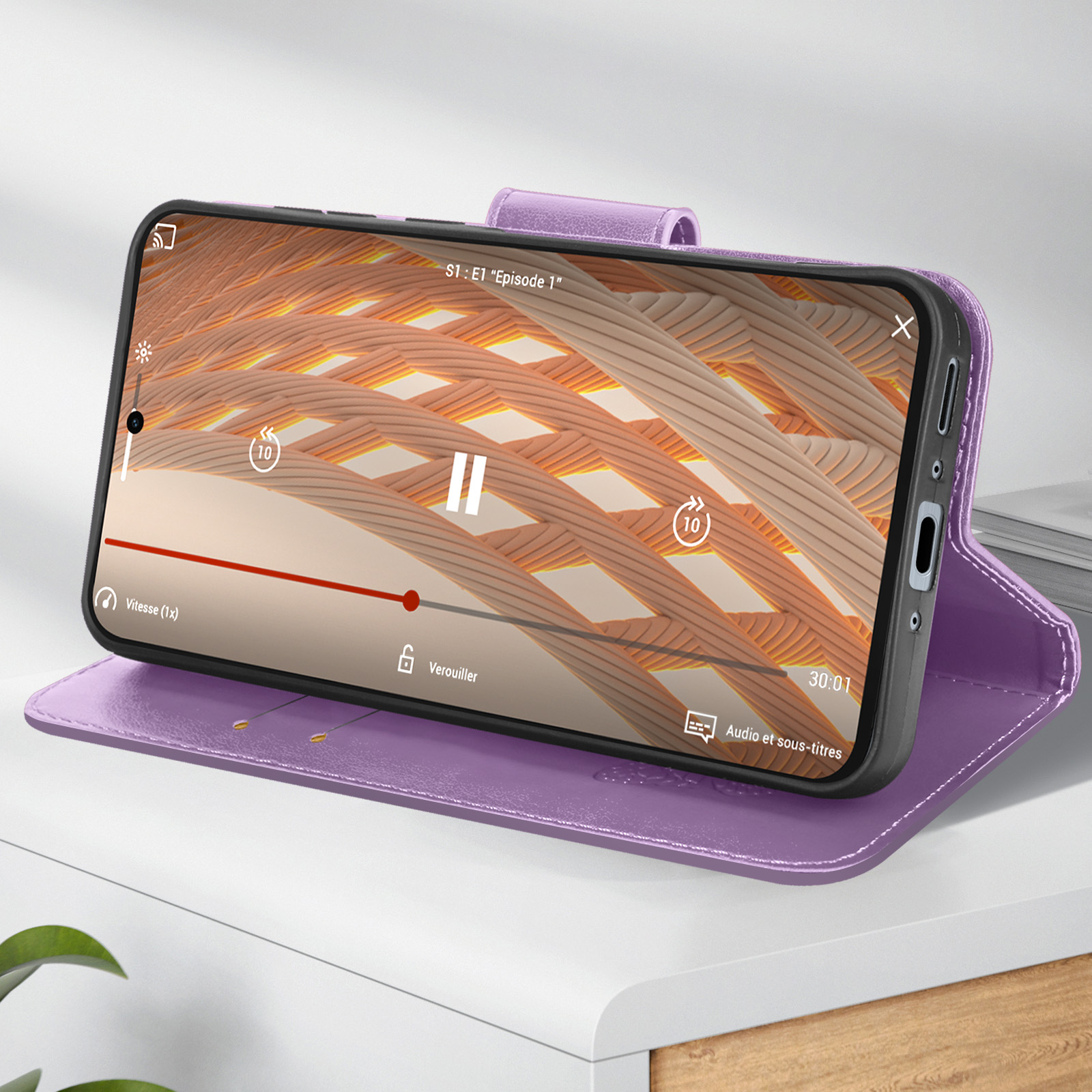 Telefono in custodia viola, che riproduce video, su superficie bianca.