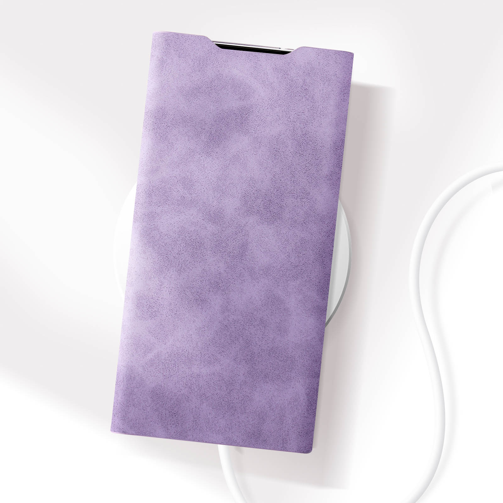 Una custodia per telefono viola appoggiata su un caricatore wireless bianco. Un cavo bianco accanto.
