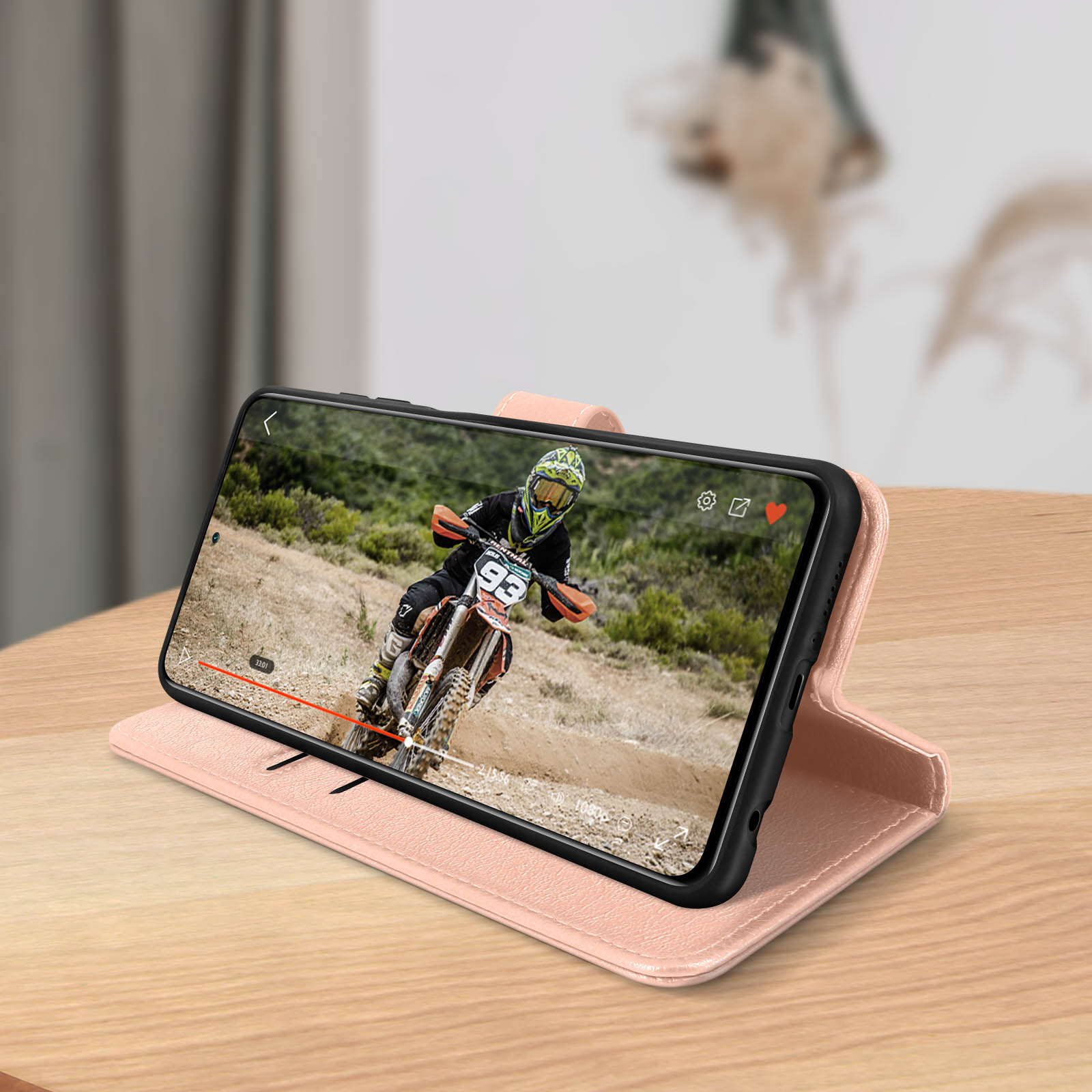 Telefono che mostra un video di una gara di motocross in una custodia rosa.