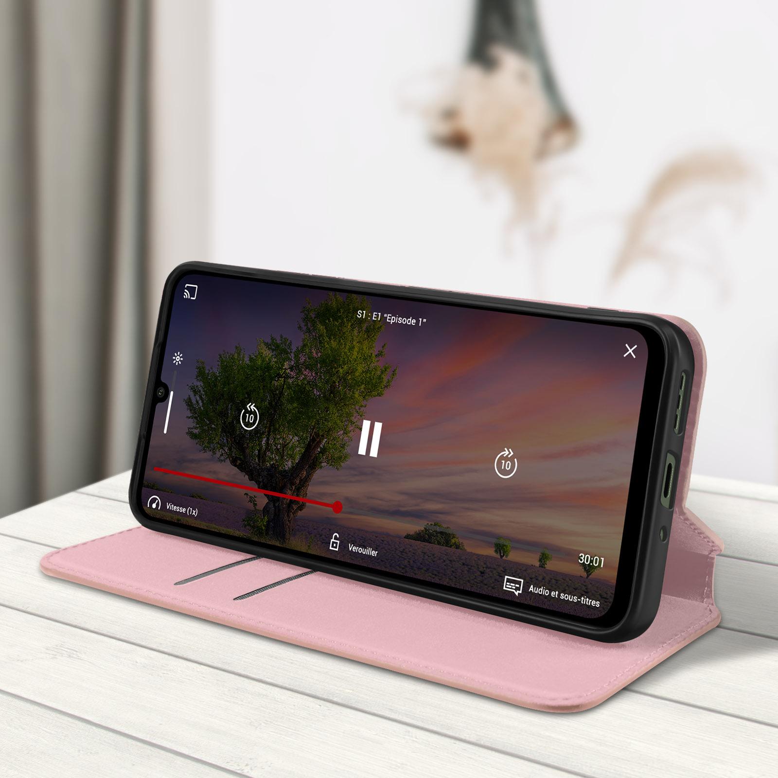 Telefono in una custodia rosa, aperto. Superficie rosa. Riproduzione di un video.
