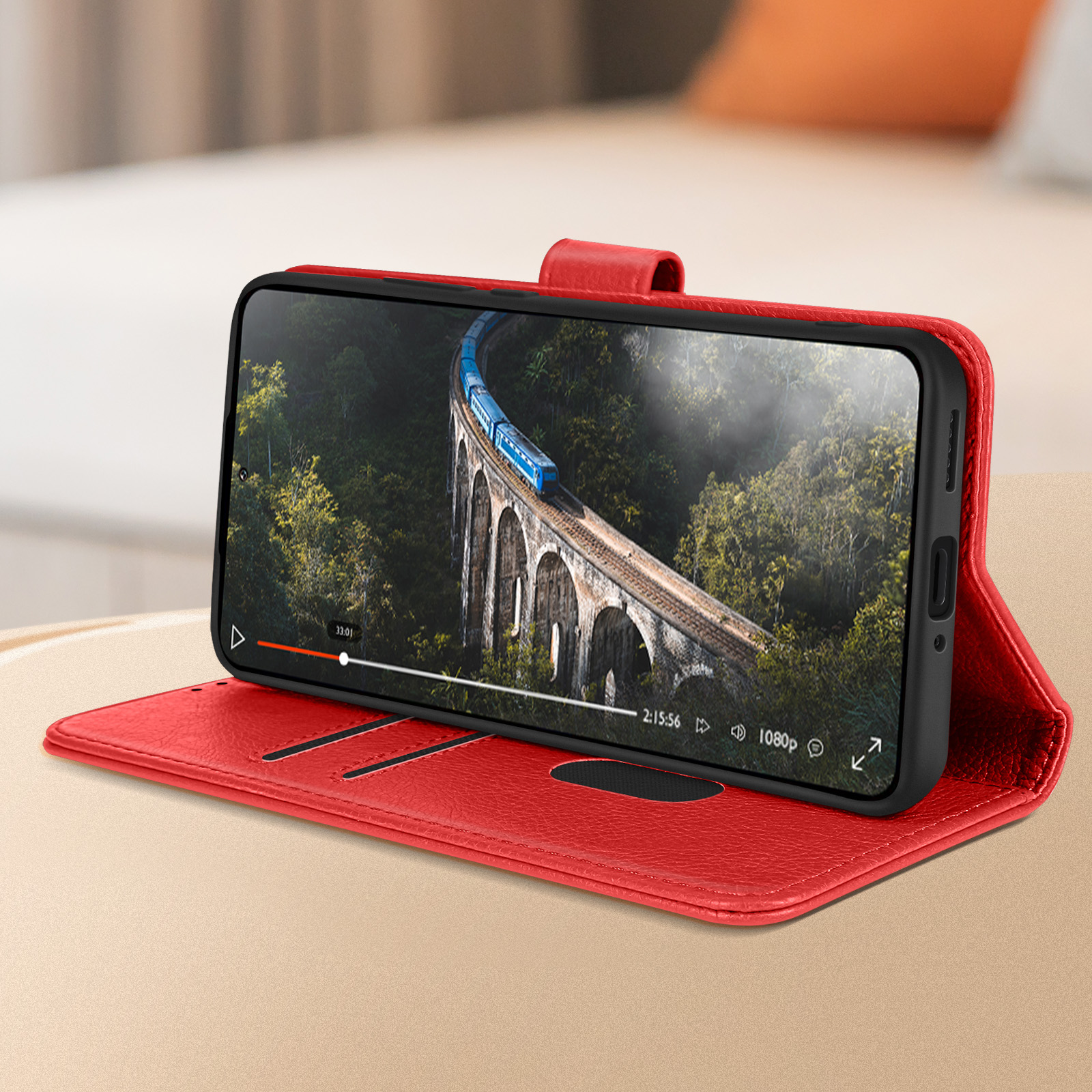 Telefono in custodia rossa, mostra un video di un ponte e un treno. Custodia aperta.