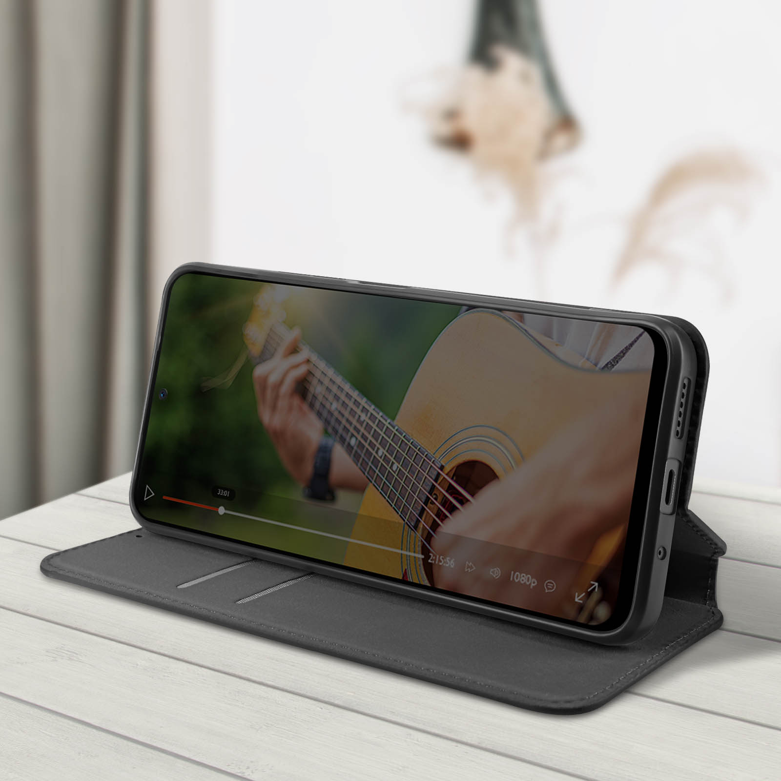 Un telefono che mostra un video di una persona che suona la chitarra, in una custodia.