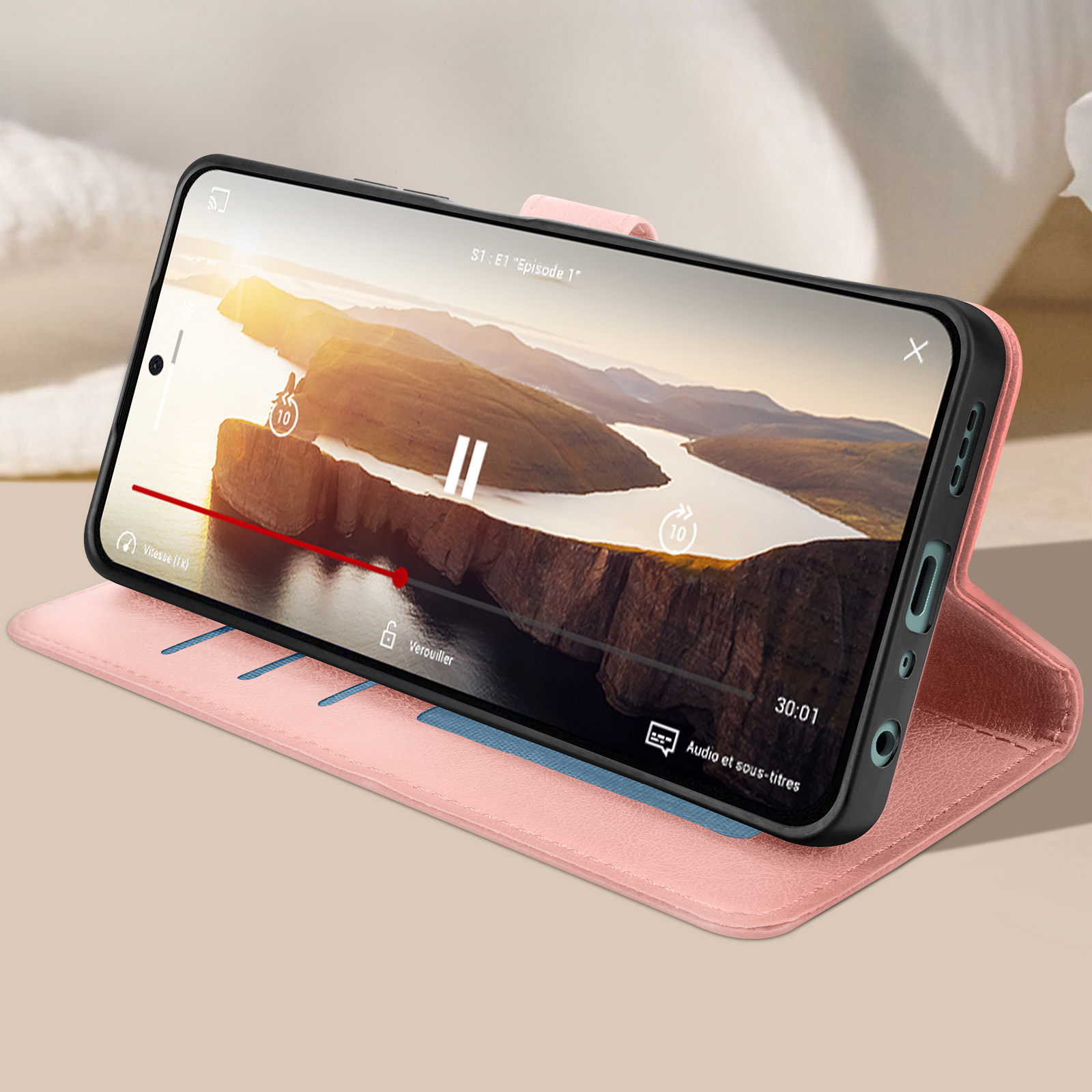 Un telefono mostra un video, tenuto da una custodia rosa. Ha degli slot per schede.