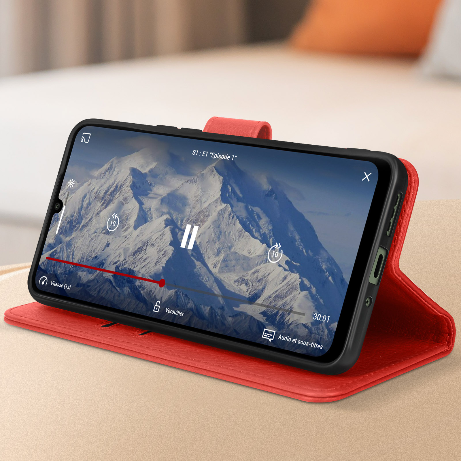Telefono che riproduce un video, in una custodia rossa, su una superficie chiara. Paesaggio montano sullo schermo.