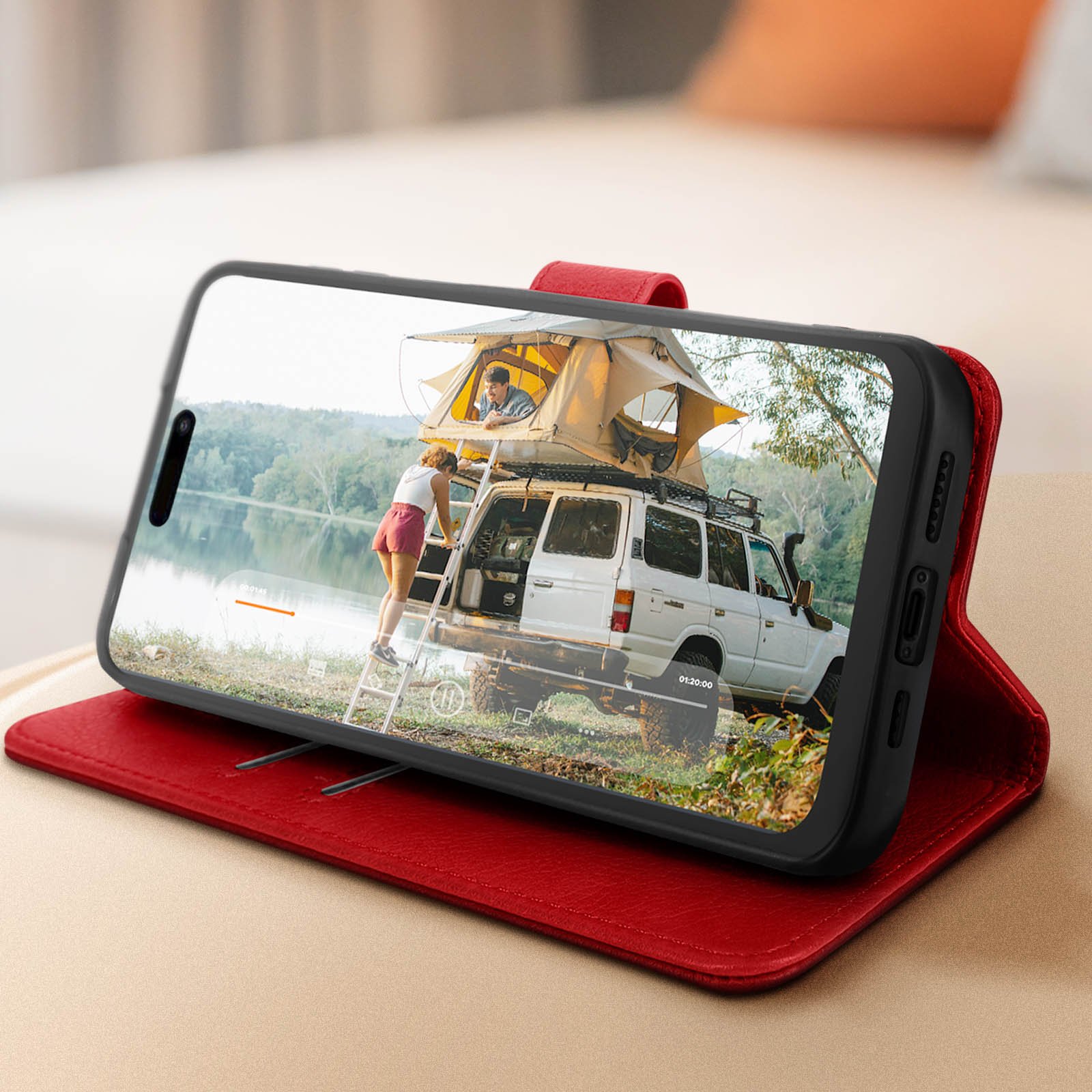 Telefono in custodia rossa con video di auto con persone. Sfondo: lago e alberi.