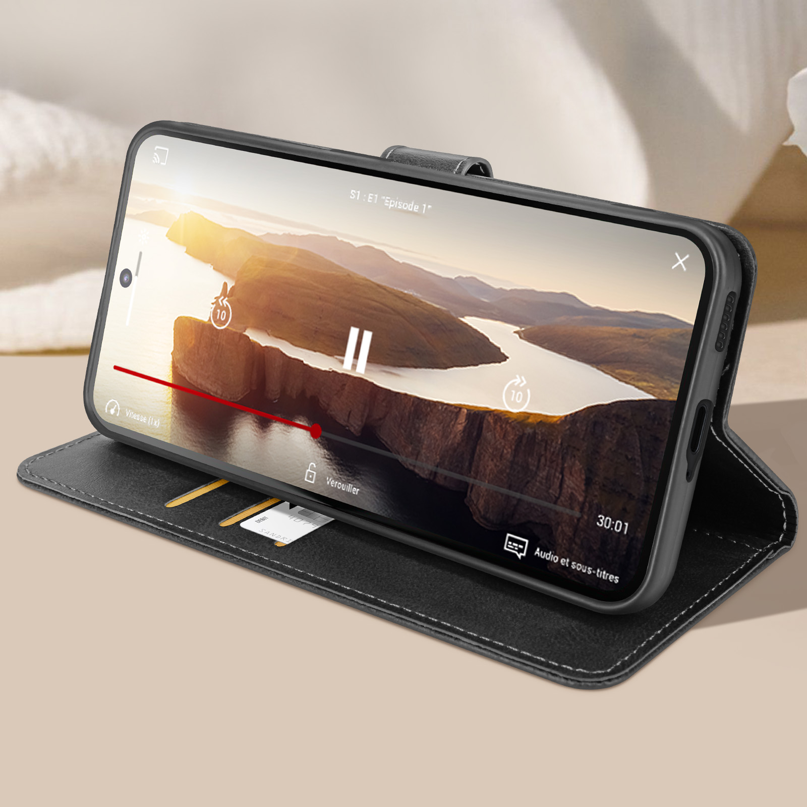 Custodia nera per telefono che mostra un video. Custodia aperta su un tavolo, carte di credito visibili.