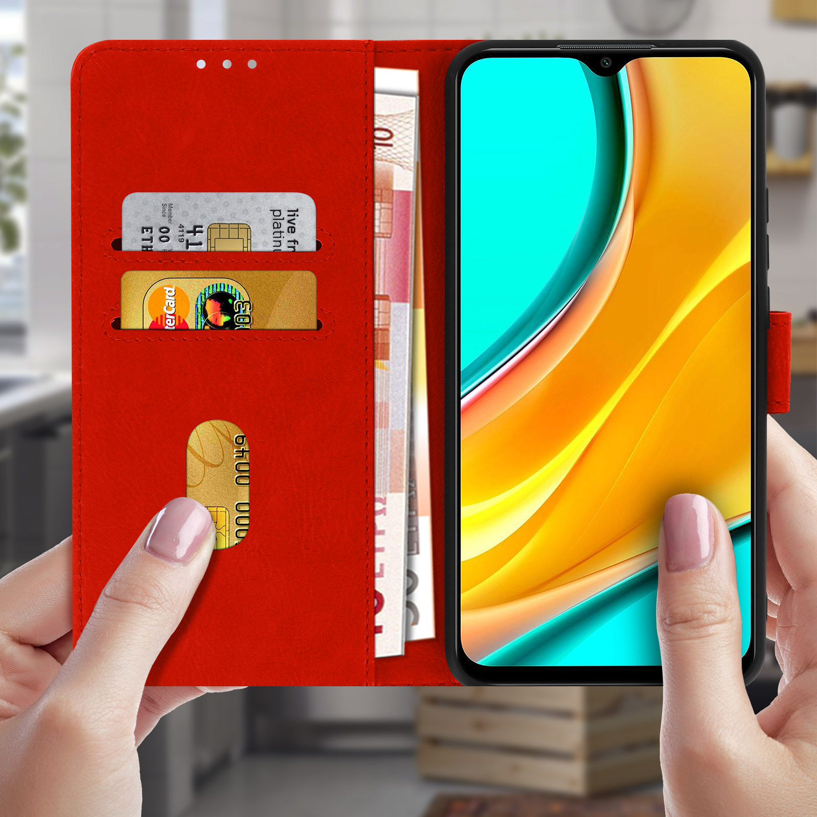 Una custodia per telefono rossa, aperta, rivela un telefono con carte di credito e denaro. La custodia viene tenuta.