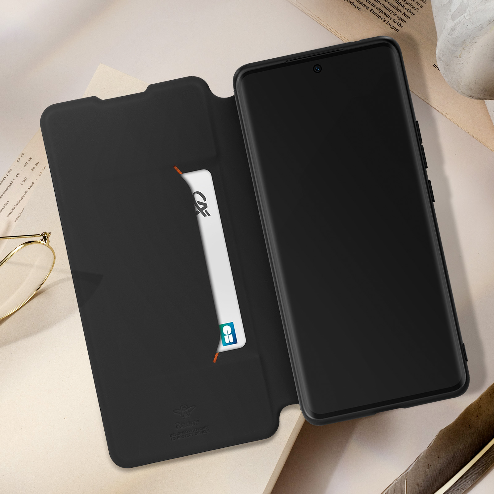 Schwarze Handyhülle offen, mit Karte und Telefon. Stift und Brille auf dem Tisch.