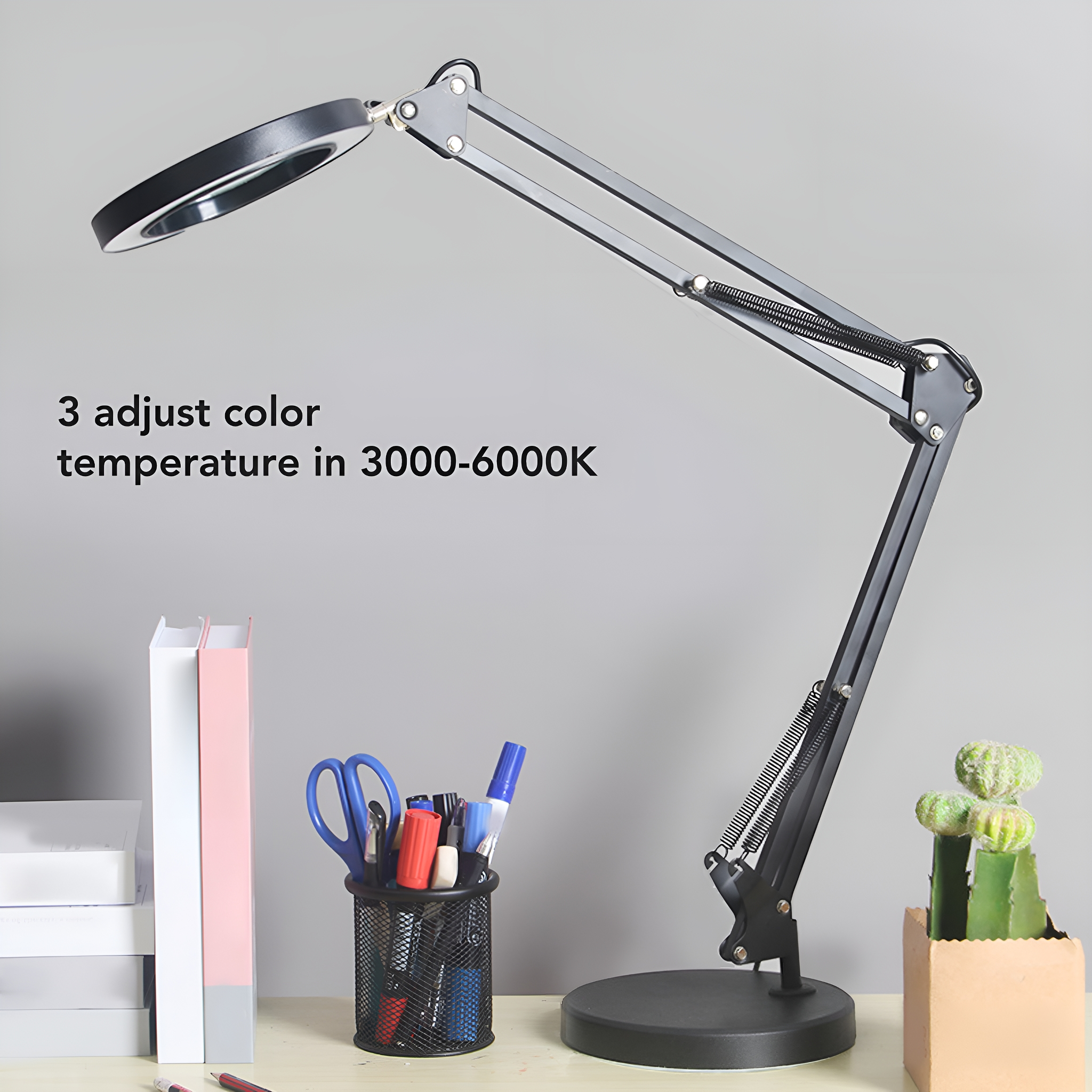 Eine schwarze Schreibtischlampe mit Lupe, Stiften, Schere und einer kleinen Pflanze.