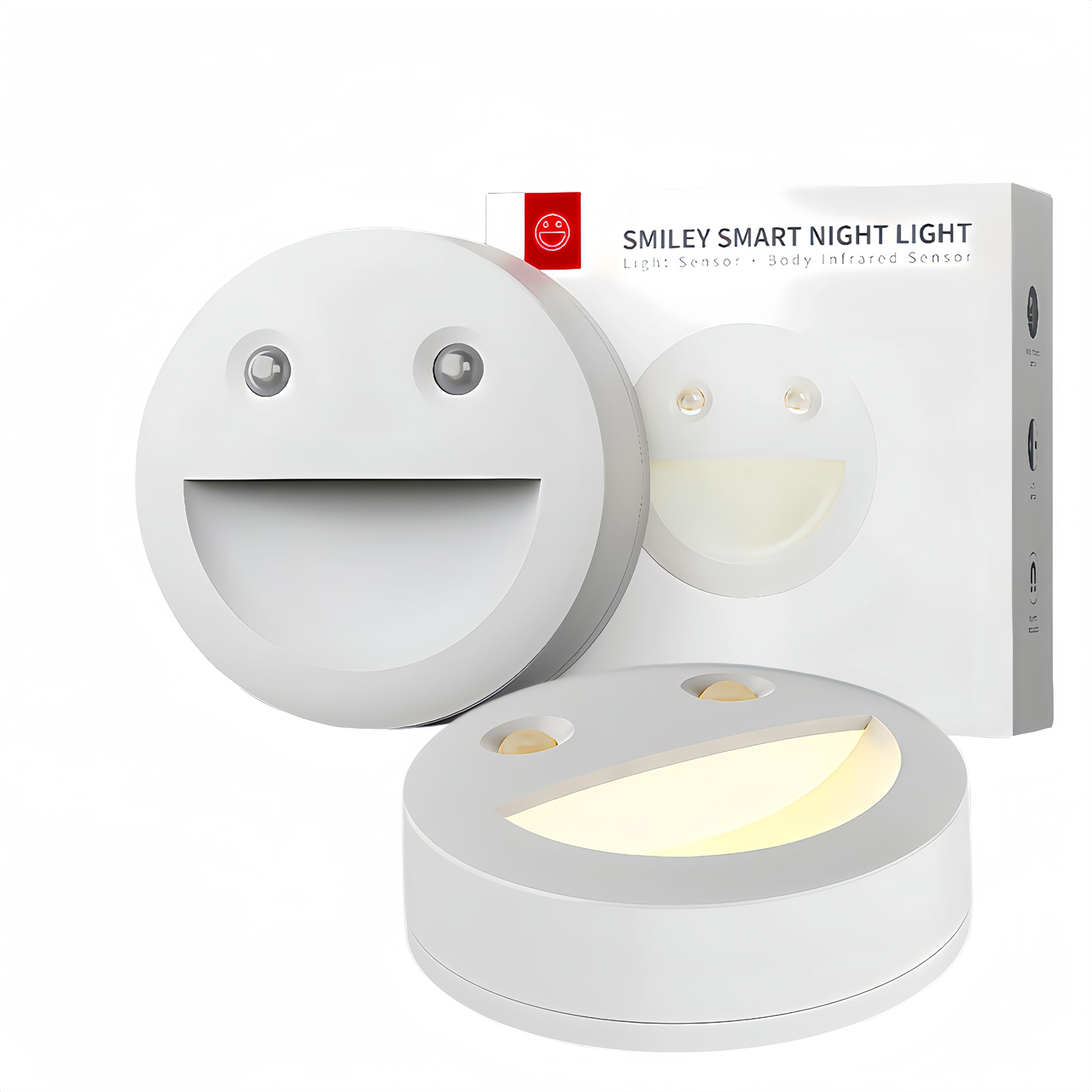 Zwei weiße Nachtlichter mit Smiley-Gesicht und einer Box, auf weißer Oberfläche. Die Lichter lächeln.