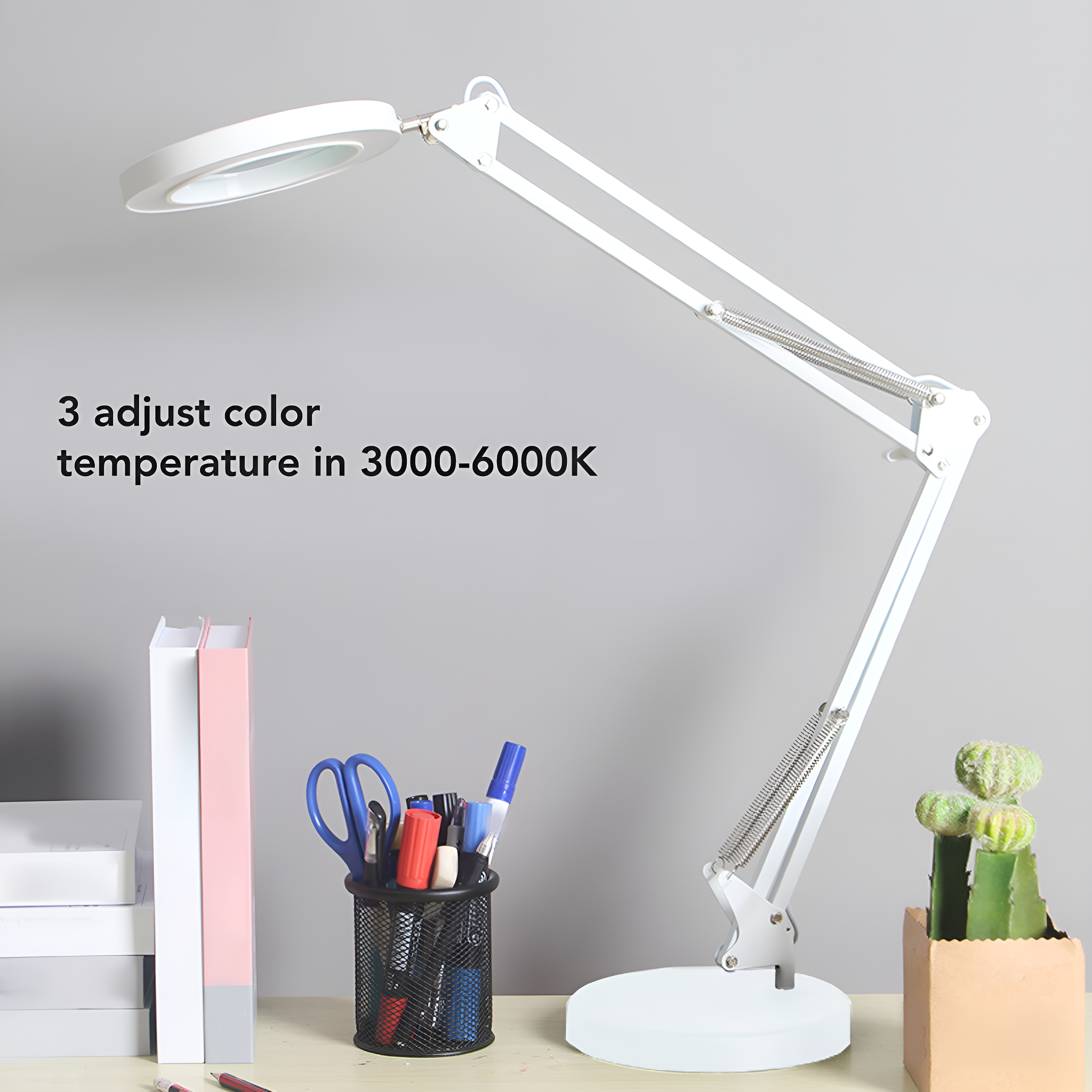 Weiße, verstellbare Schreibtischlampe mit Lupe. Ein Stifthalter und einige Bücher stehen auf dem Schreibtisch.