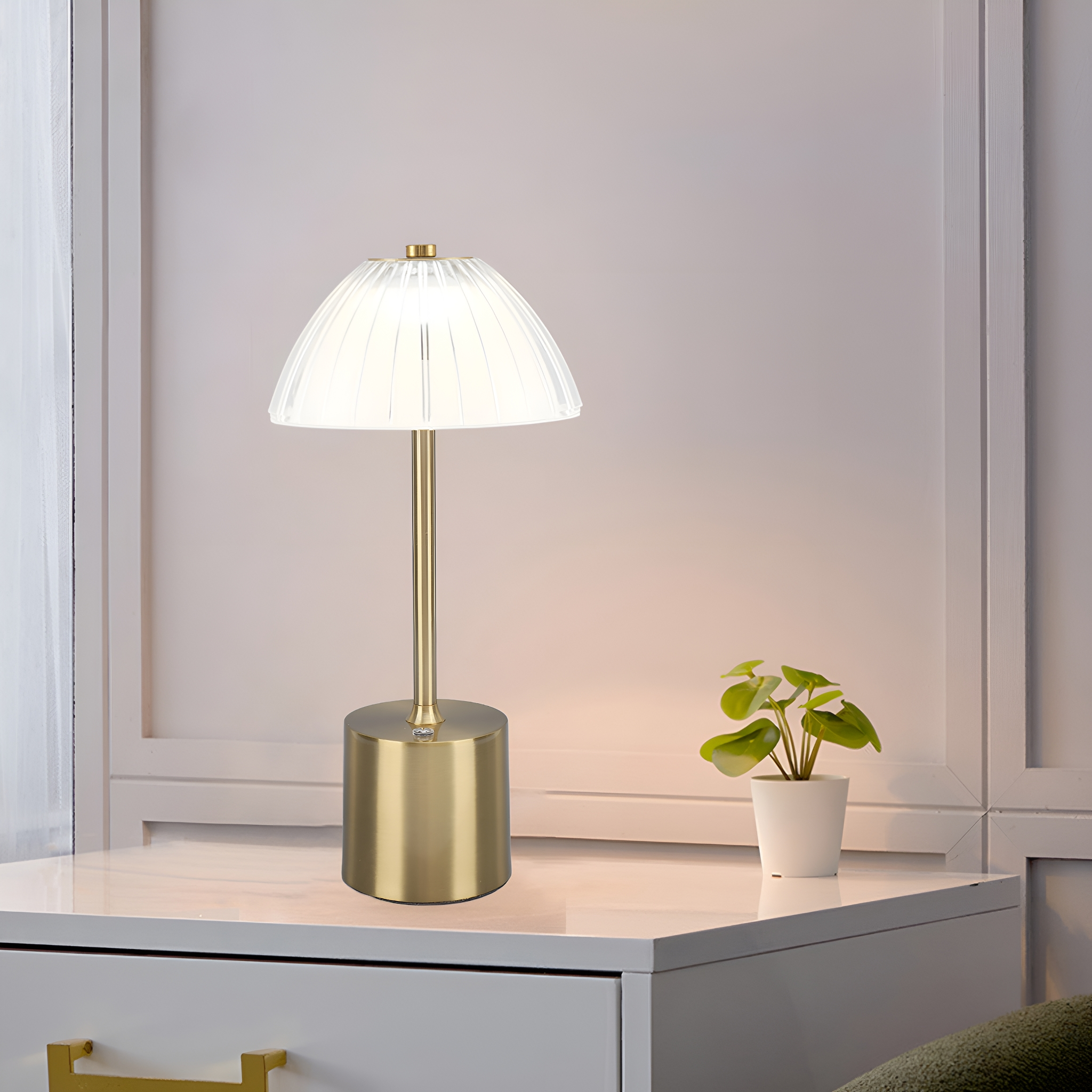 Goldene Tischlampe auf weißer Oberfläche. Die Lampe hat einen runden Sockel und einen geriffelten Schirm.
