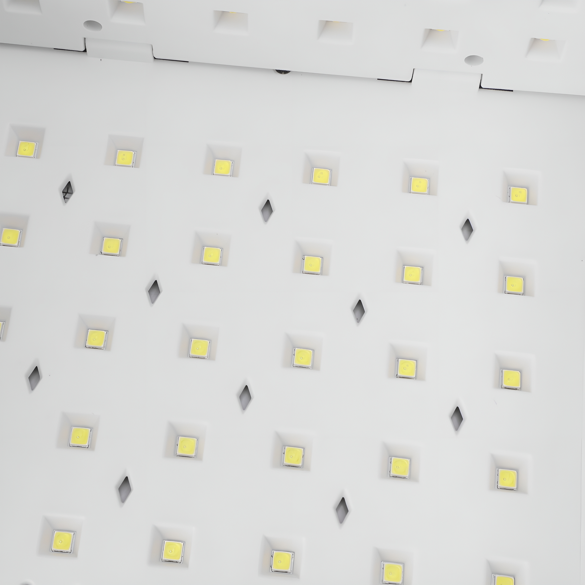 Eine weiße Oberfläche mit mehreren kleinen, quadratischen, gelben Lichtern, die in einem Rastermuster angeordnet sind.